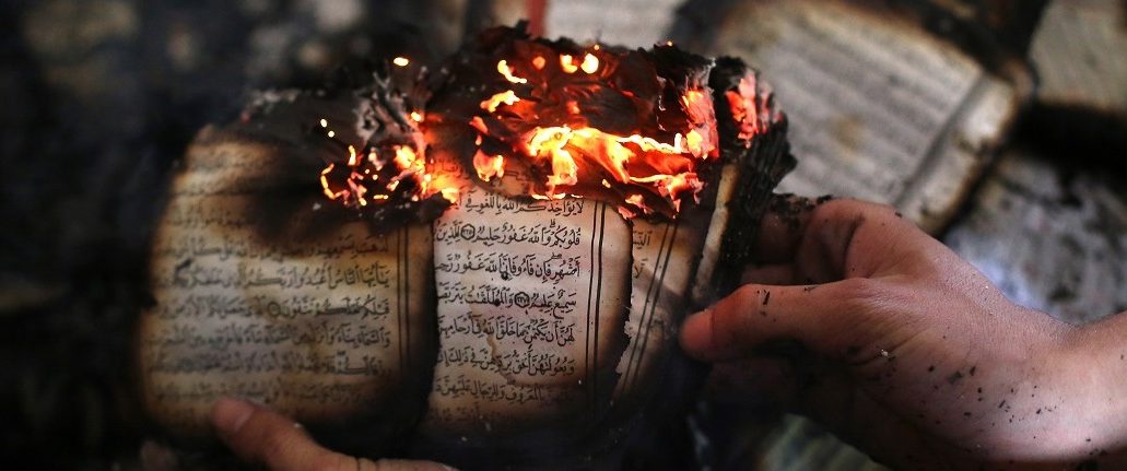 A Palestinian man displays a copy of Islam's holy book, the Koran, still burning inside a mosque that was set ablaze by Israeli settlers in al-Mughayir, in the occupied West Bank near the Jewish settlement of Shilo, on November 12, 2014. Israeli settlers torched the West Bank mosque in an apparent revenge attack, after separate Palestinian knife attacks the previous day killed a settler in the southern Western Bank and an Israeli soldier in Tel Aviv. Abbas Momani/AFP/Getty Images.