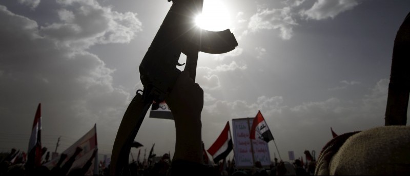 A Houthi follower rises a weapon as he attends a rally marking one year of Saudi-led air strikes, in Yemen