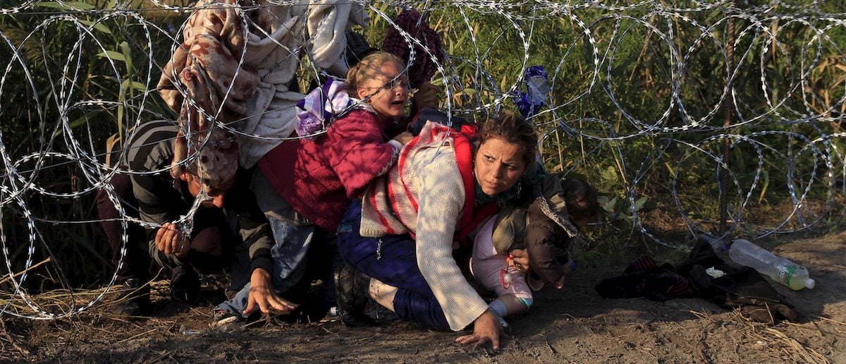 Syrian migrants cross under a fence as they enter Hungary at the border with Serbia, near Roszke, August 27, 2015. Hungary made plans on Wednesday to reinforce its southern border with helicopters, mounted police and dogs, and was also considering using the army as record numbers of migrants, many of them Syrian refugees, passed through coils of razor-wire into Europe. REUTERS/Bernadett Szabo 