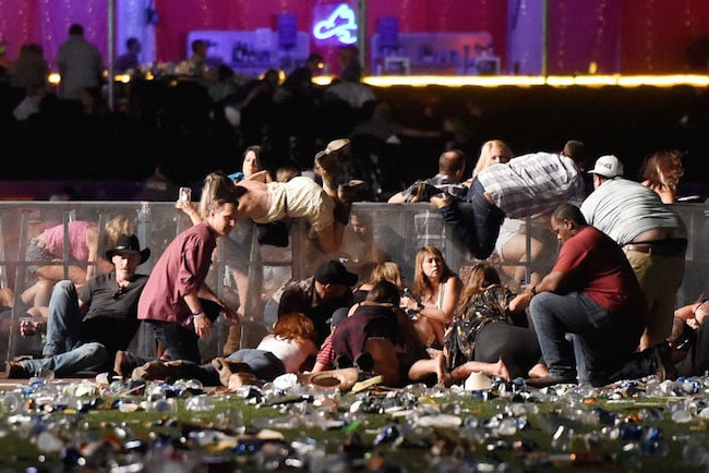 People scramble for shelter at the Route 91 Harvest country music festival after apparent gun fire was heard on October 1, 2017 in Las Vegas. (Photo by David Becker/Getty Images)