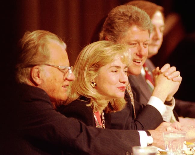 Rev. Billy Graham sits with first lady Hillary Clinton and President Bill Clinton at the head table during a prayer breakfast at the Washington Hilton hotel Feb 04, 1993. REUTERS/Gary Cameron