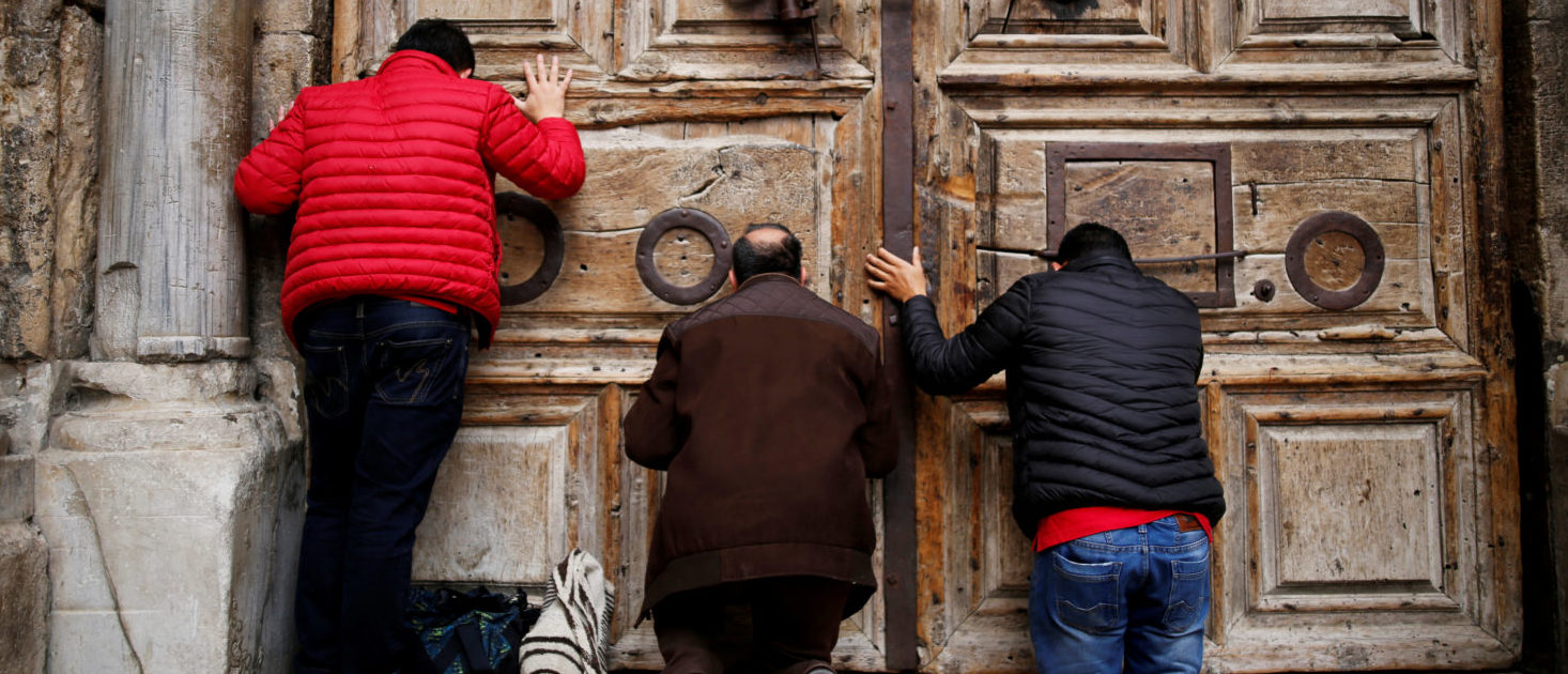 Worshippers kneel and pray in front of the closed doors of the Church of the Holy Sepulchre in Jerusalem's Old City, February 25, 2018. REUTERS/Amir Cohen     
