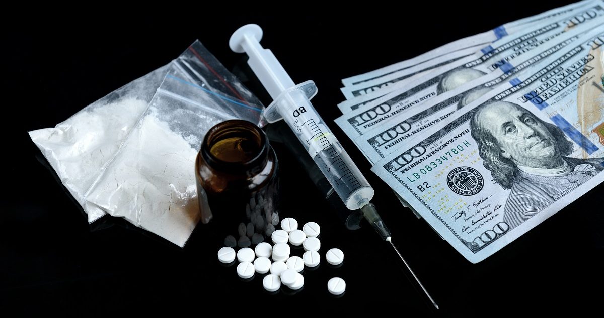 Drug heroin, syringes, pills and dollar money on black background. Crime and addiction concept. natali_ploskaya/Shutterstock