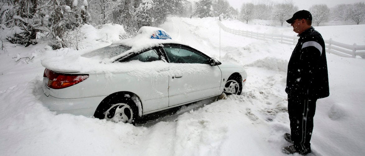A Domino's Pizza delivery man ponders his next move after his vehicle got stucked on a snow-covered road in Great Falls, Virginia, February 6, 2010. A blizzard producing heavy snow and powerful winds pummeled the U.S. mid-Atlantic on Saturday, causing at least two fatalities and paralyzing travel in the region. Snowfall totals of 20 to 30 inches (51 to 76 cm) are forecast from Virginia to southern New Jersey by Saturday evening when the storm is expected to move out to sea. REUTERS/Hyungwon Kang    (UNITED STATES - Tags: ENVIRONMENT TRANSPORT) - GM1E62705BI01