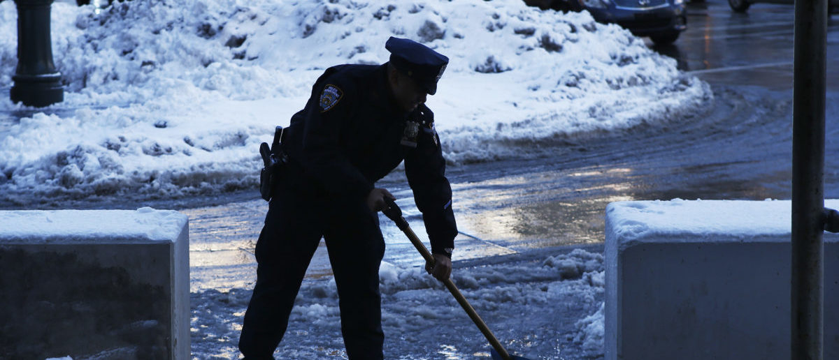 A New York Police Officer clears snow and ice on a street after a night of snow in New York, February 14, 2014. A four-day-old storm that dumped heavy snow, sleet, and freezing rain across the northern U.S. East Coast overnight should taper off as Friday wears on, forecasters said, bringing a measure of relief to winter-weary residents and travelers.REUTERS/Eduardo Munoz