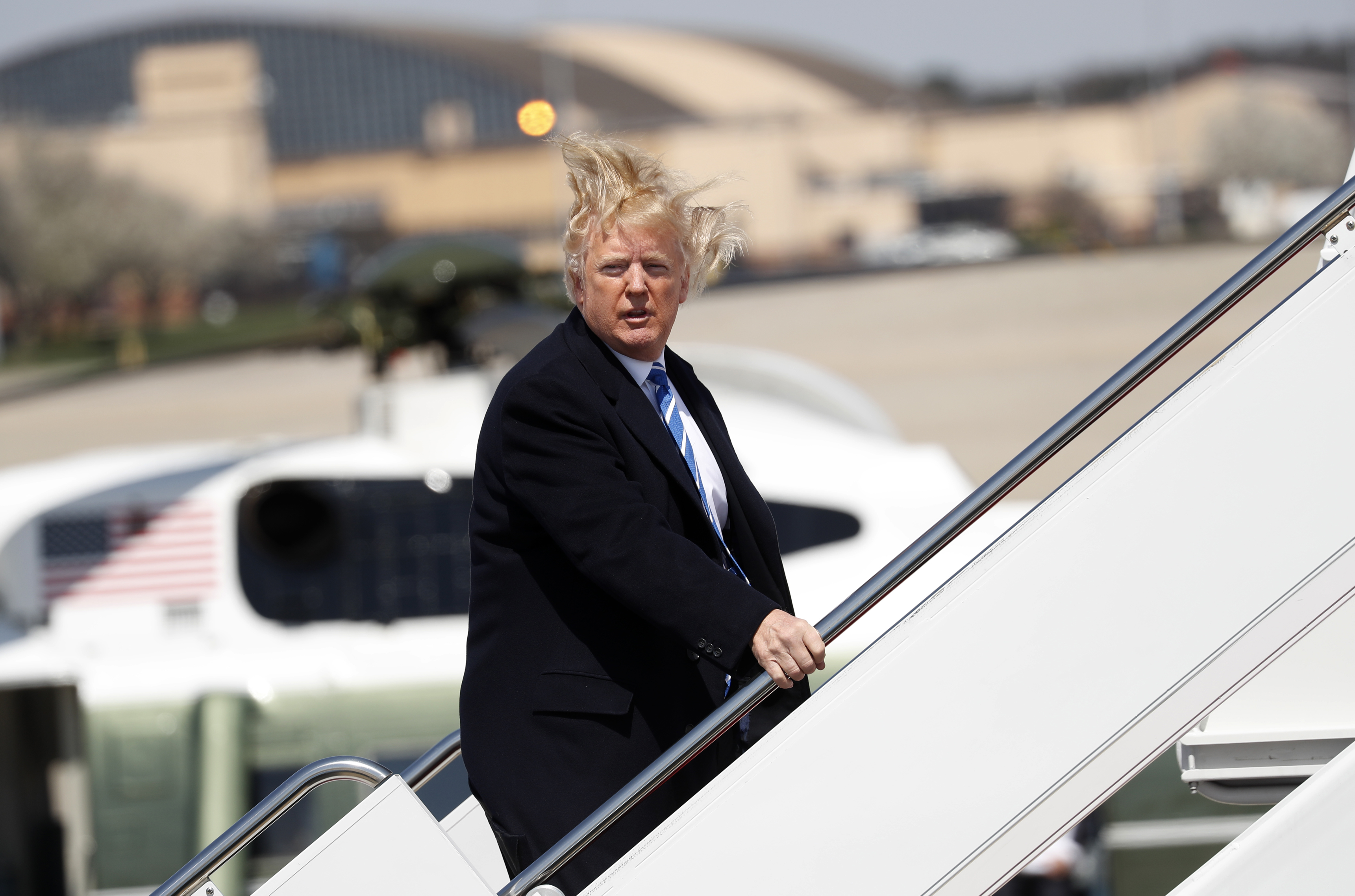 U.S. President Donald Trump yells over to members of the news media as he boards Air Force One on a windy day at Joint Base Andrews, Maryland before departing en route to an event in West Virginia, U.S., April 5, 2018. (REUTERS/Kevin Lamarque)