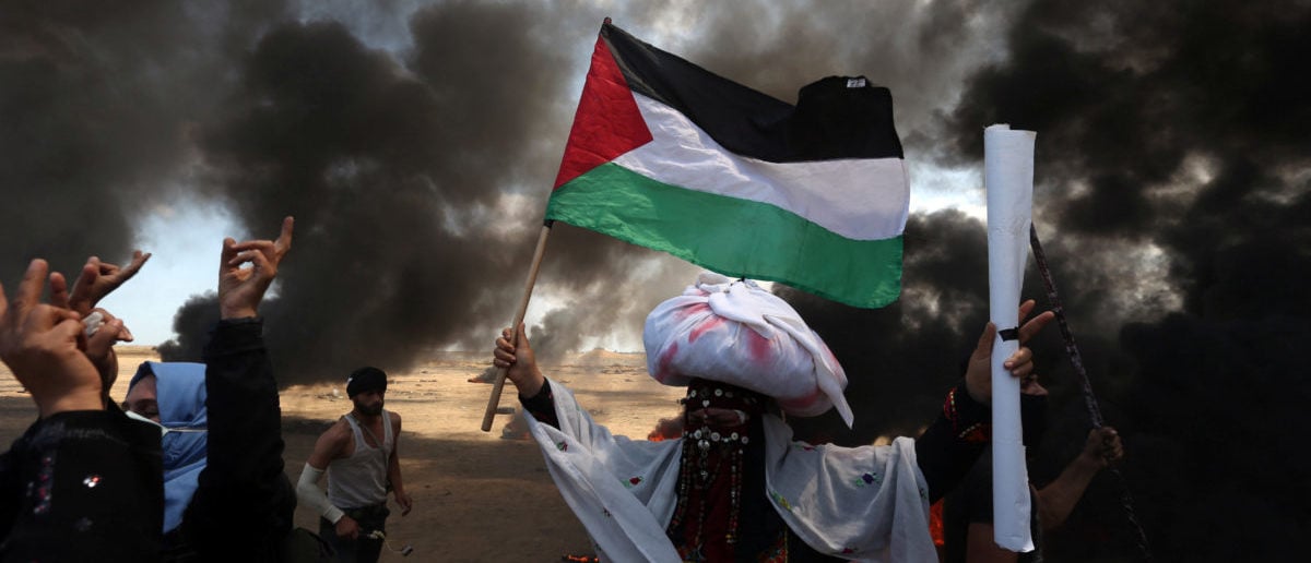 A female demonstrator holds a Palestinian flag during a protest against U.S. embassy move to Jerusalem and ahead of the 70th anniversary of Nakba, at the Israel-Gaza border in the southern Gaza Strip May 14, 2018. REUTERS/Ibraheem Abu Mustafa