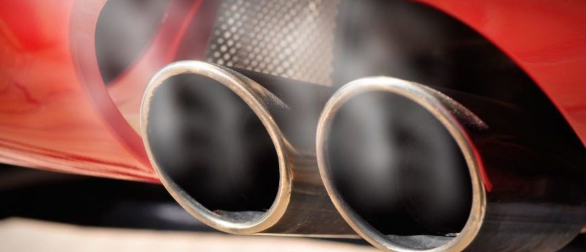 Close up of a red car dual exhaust pipe with smoke around it (Shutterstock/ruigsantos) | Trump Dings Another Emission Rule 