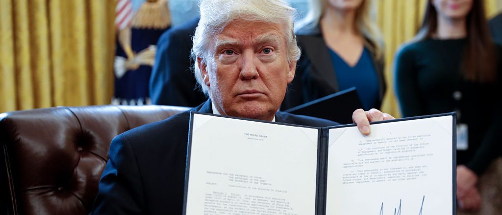 President Donald Trump displays one of five executive orders he signed related to the oil pipeline industry in the oval office of the White House January 24, 2017 in Washington, D.C. (Photo by Shawn Thew-Pool/Getty Images)q