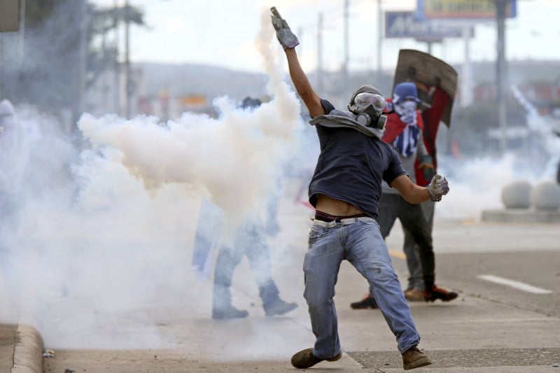 A demonstrator throws a tear gas canister during a protest as Honduran President Juan Orlando Hernandez is sworn in for a new term in Tegucigalpa, Honduras January 27, 2018. REUTERS/Edgard Garrido