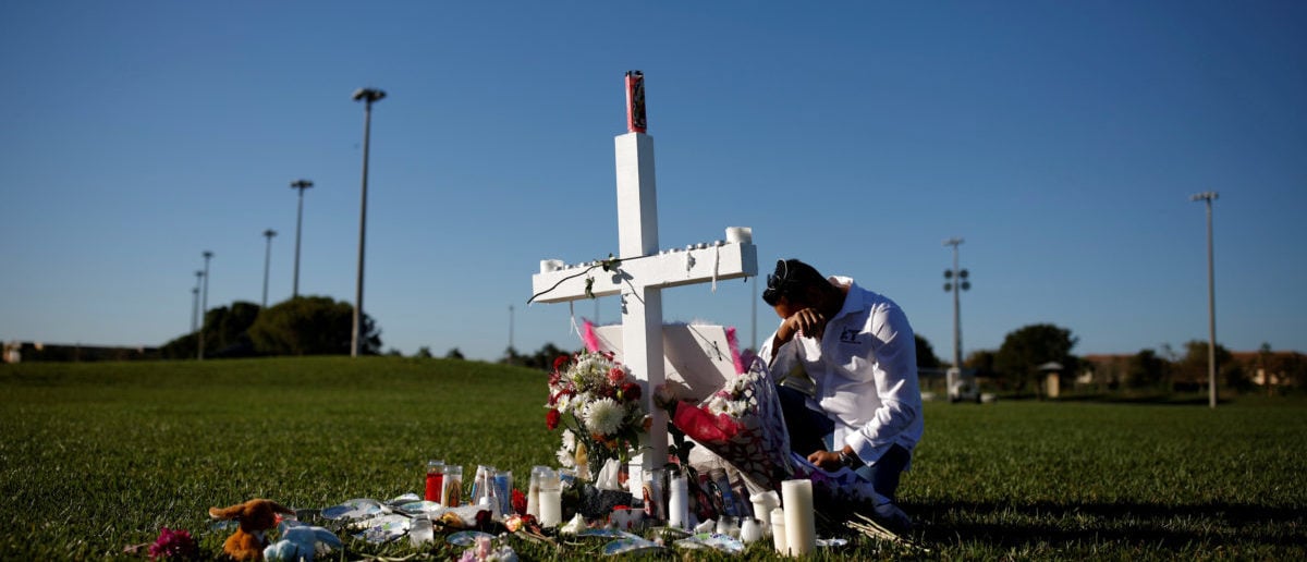 Joe Zevuloni mourns in front of a cross placed in a park to commemorate the victims of the shooting at Marjory Stoneman Douglas High School, in Parkland, Florida, U.S., February 16, 2018. REUTERS/Carlos Garcia Rawlins   