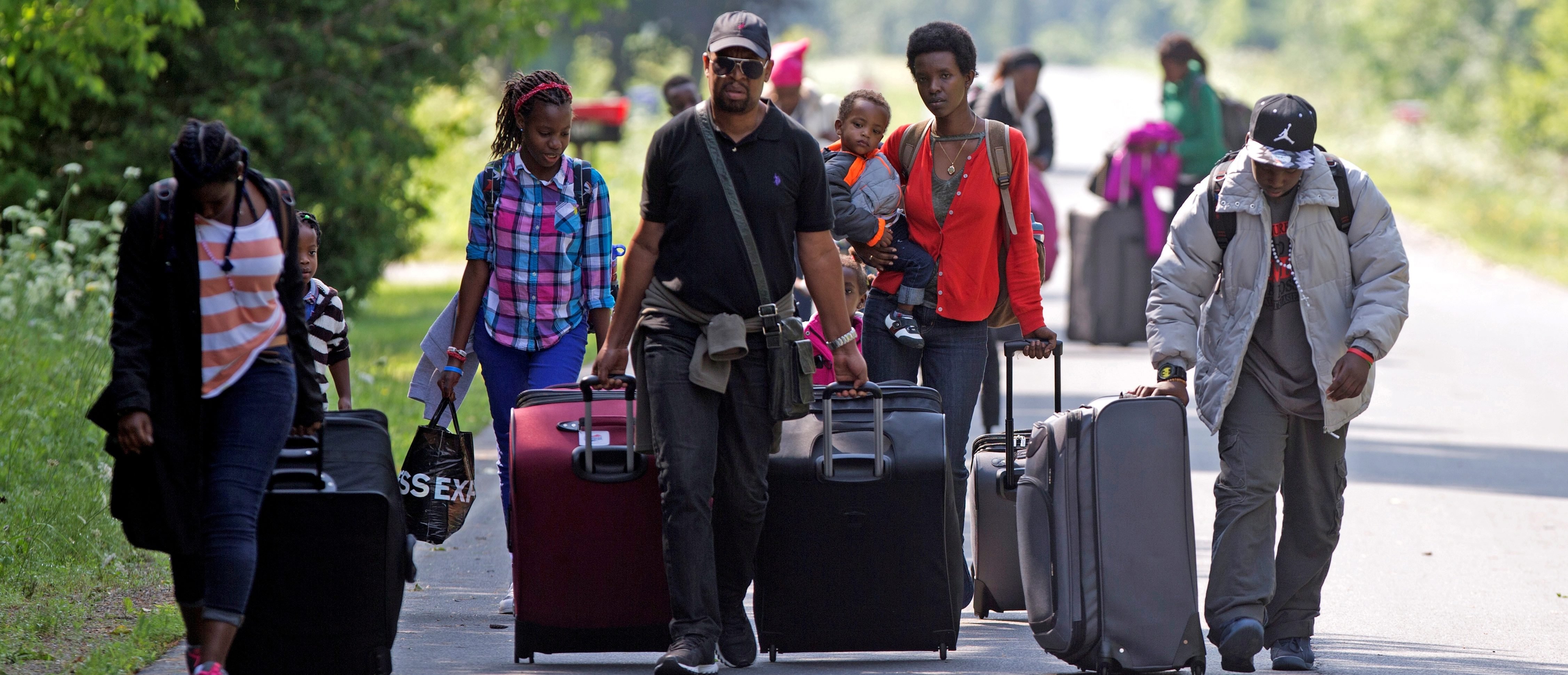 FILE PHOTO: Three families that claimed to be from Burundi walk down Roxham Road to cross into Quebec at the US-Canada border in Champlain, New York, August 3, 2017. REUTERS/Christinne Muschi/File Photo