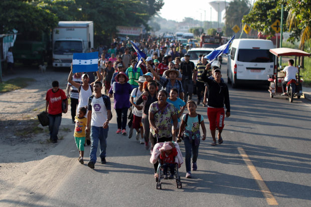 Central American migrants, part of a caravan trying to reach the U.S., shout slogans as they walk along the road, in Ciudad Hidalgo, Mexico October 26, 2018. REUTERS/Carlos Garcia Rawlins