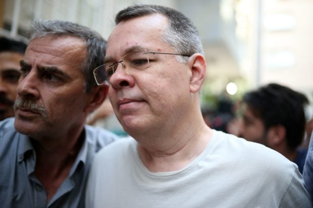 Pastor Andrew Craig Brunson (R), escorted by Turkish plain clothes police officers as he arrives at his house on July 25, 2018 in Izmir. - A Turkish court on July 25, 2018 ruled to place under house arrest an American pastor who has been imprisoned for almost two years on terror-related charges in a case that has raised tensions with the United States, state media said. The state-run Anadolu news agency said he was being put under house arrest, although it was not clear if he had already left prison. (Photo by STRINGER / AFP) (Photo credit should read STRINGER/AFP/Getty Images)