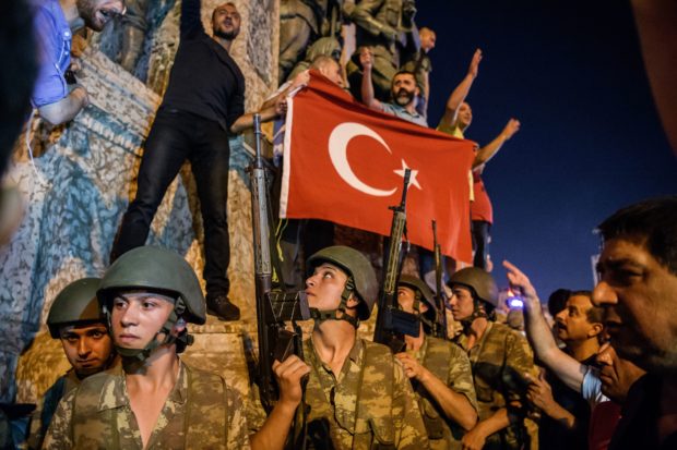 TOPSHOT - EDITORS NOTE: Graphic content / Turkish solders stay with weapons at Taksim square as people protest against the military coup in Istanbul on July 16, 2016. Turkish military forces on July 16 opened fire on crowds gathered in Istanbul following a coup attempt, causing casualties, an AFP photographer said. The soldiers opened fire on grounds around the first bridge across the Bosphorus dividing Europe and Asia, said the photographer, who saw wounded people being taken to ambulances. / AFP / OZAN KOSE (Photo credit should read OZAN KOSE/AFP/Getty Images)
