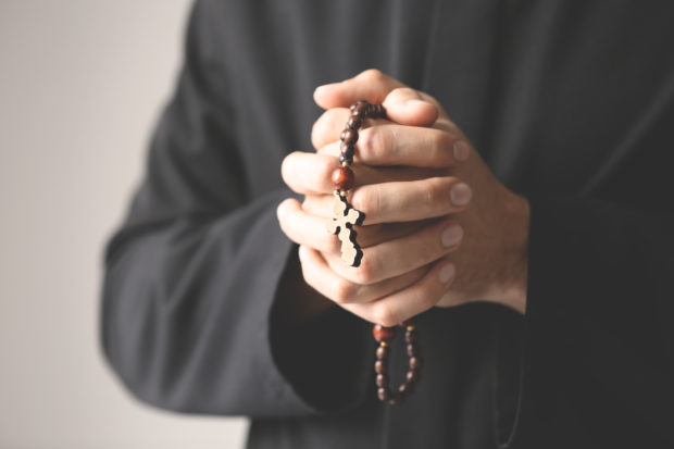 A Catholic priest carrying rosary beads (Shutterstock/Africa Studio)