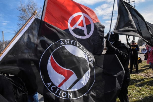 Members of the Great Lakes anti-fascist organization (Antifa) fly flags during a protest against the Alt-right outside a hotel in Warren, Michigan, U.S., March 4, 2018. REUTERS/Stephanie Keith - RC1B5E31E310