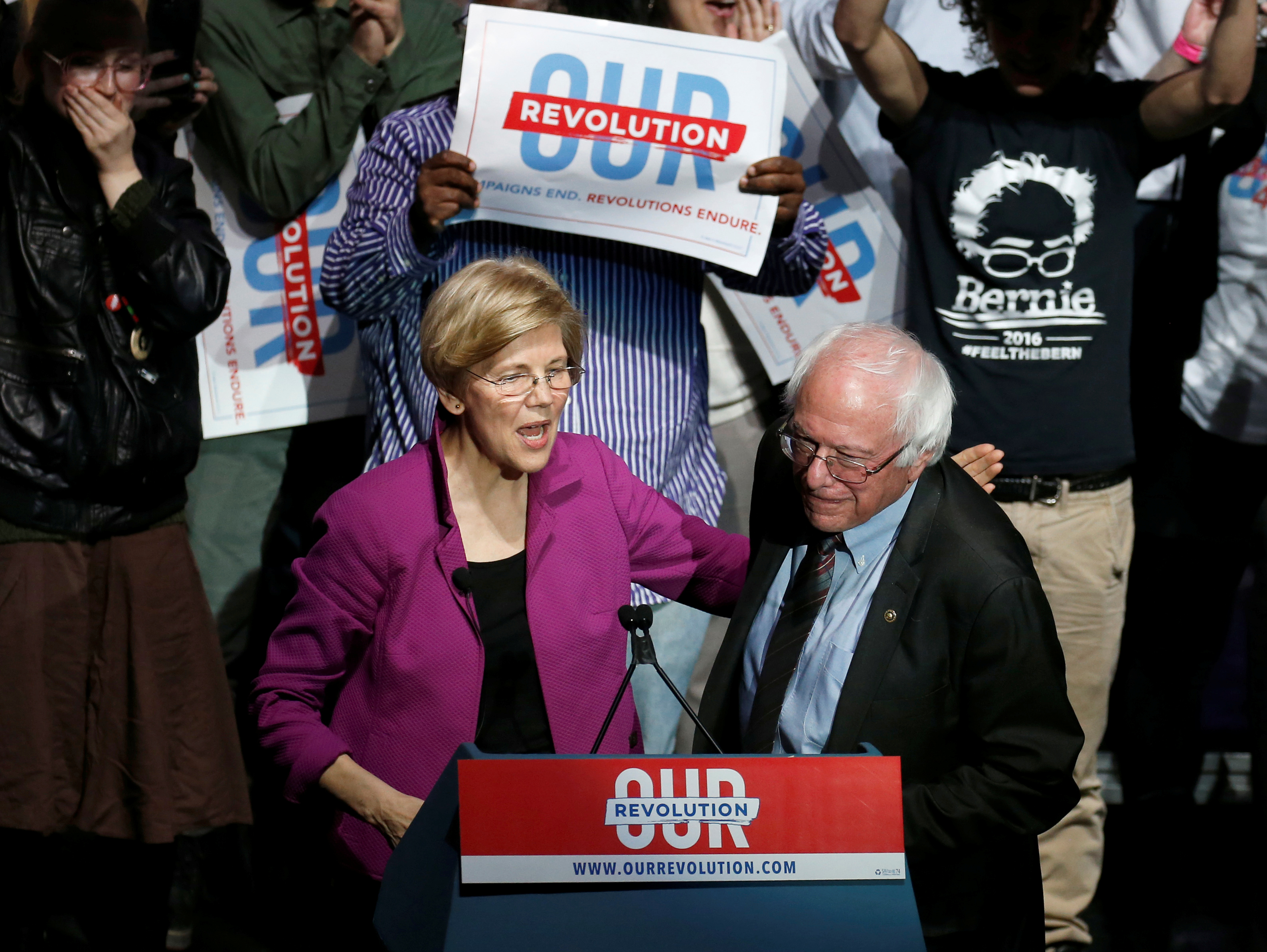 U.S. Senator Warren puts her arm around U.S. Senator Sanders after introducing him at a Our Revolution rally in Boston