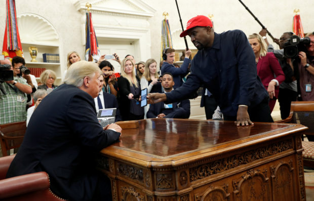 Rapper Kanye West shows President Donald Trump his mobile phone during a meeting in the Oval Office at the White House in Washington, U.S., October 11, 2018. REUTERS/Kevin Lamarque - RC15F17A7E00