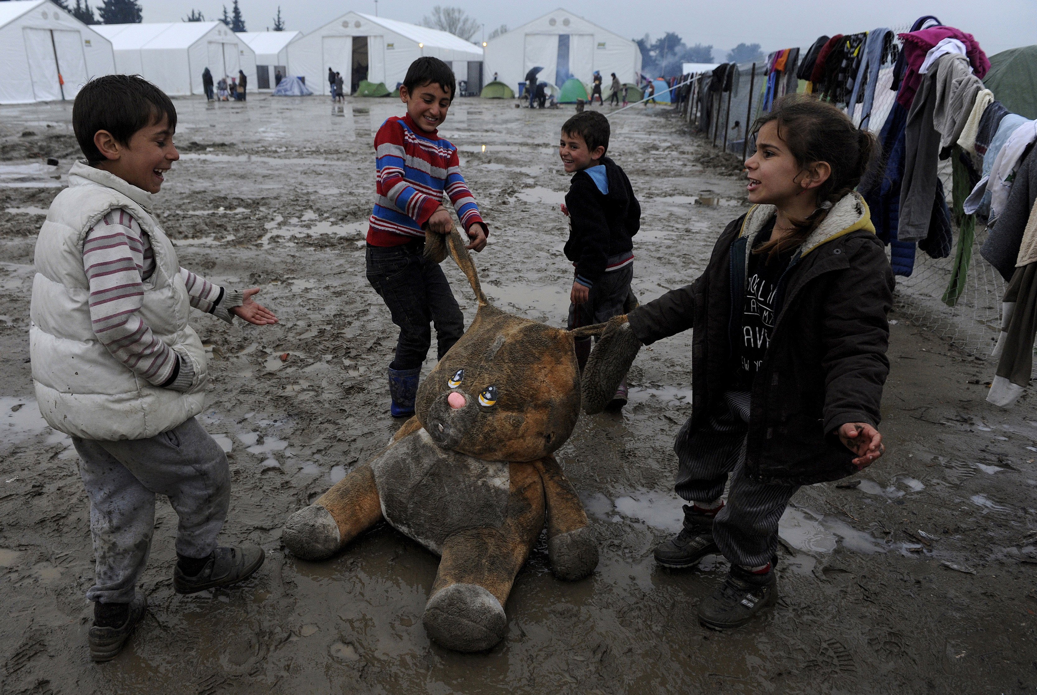 Refugee children play with a stuffed toy at a muddy makeshift camp at the Greek-Macedonian border, near the village of Idomeni, Greece March 15, 2016. REUTERS/Alexandros Avramidis