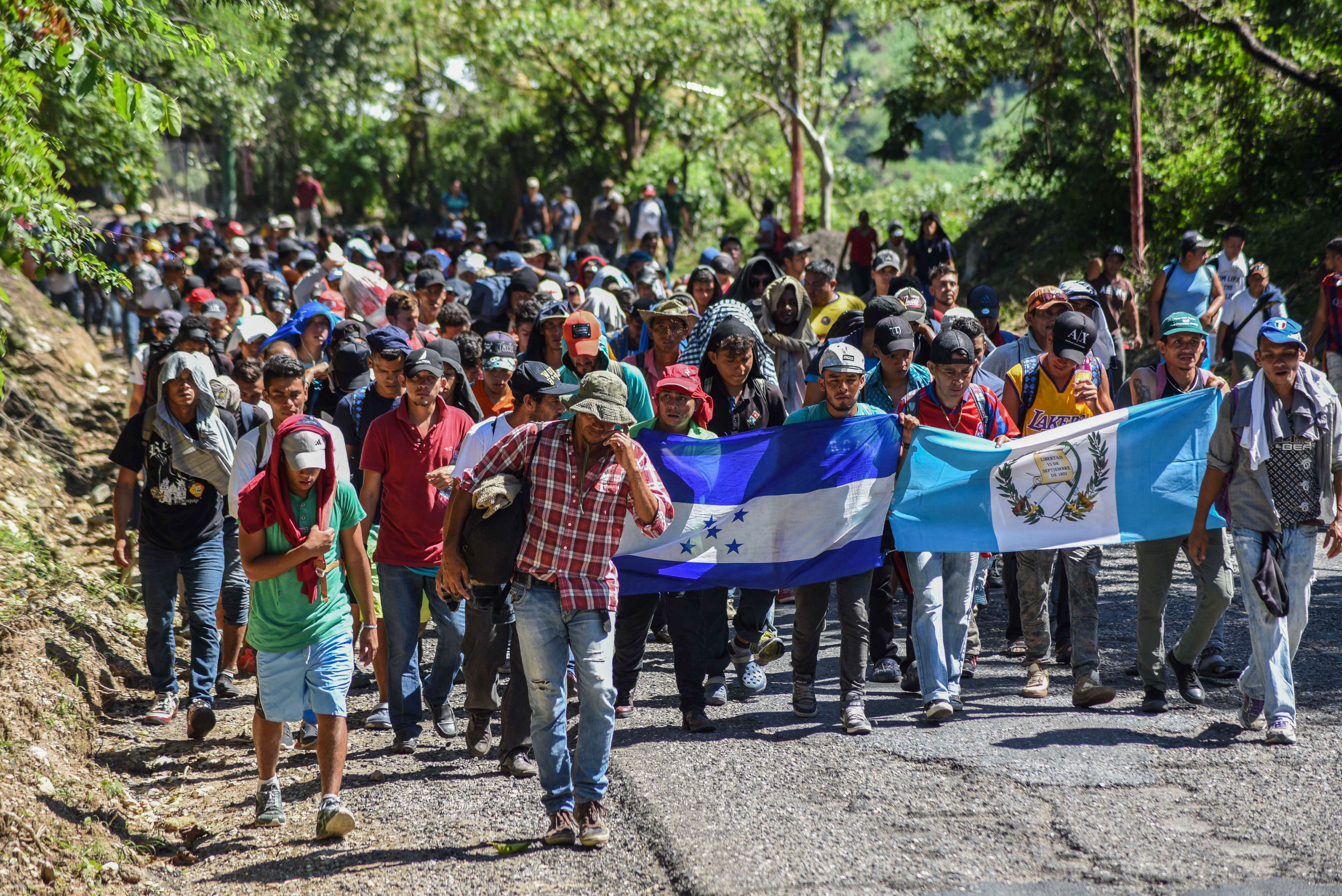 TOPSHOT - Honduran migrants take part in a new caravan heading to the US with Honduran and Guatemalan national flags in Quezaltepeque, Chiquimula, Guatemala on October 22, 2018. - US President Donald Trump on Monday called the migrant caravan heading toward the US-Mexico border a national emergency, saying he has alerted the US border patrol and military. (Photo by ORLANDO ESTRADA / AFP) (Photo credit should read ORLANDO ESTRADA/AFP/Getty Images)