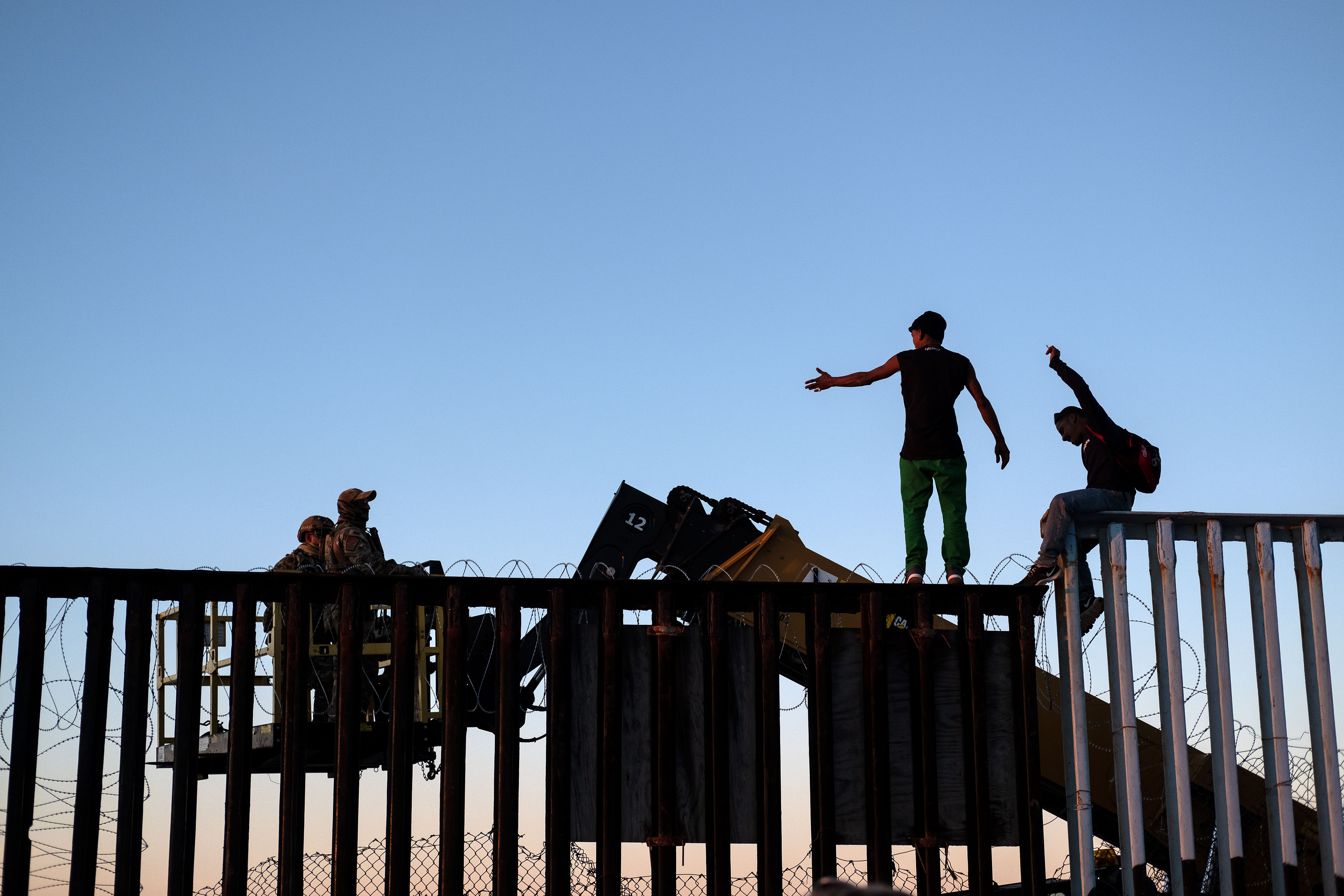 TOPSHOT - Migrants, who claimed not to be part of the Central American migrants moving towards the United States in hopes of a better life, argue with Defense Department officers after removing the barbed wire on the U.S.-Mexico border fence in Playas de Tijuana, Mexico, on November 14, 2018. - US Defence Secretary Jim Mattis said Tuesday he will visit the US-Mexico border, where thousands of active-duty soldiers have been deployed to help border police prepare for the arrival of a "caravan" of migrants. (Photo by Guillermo Arias / AFP)