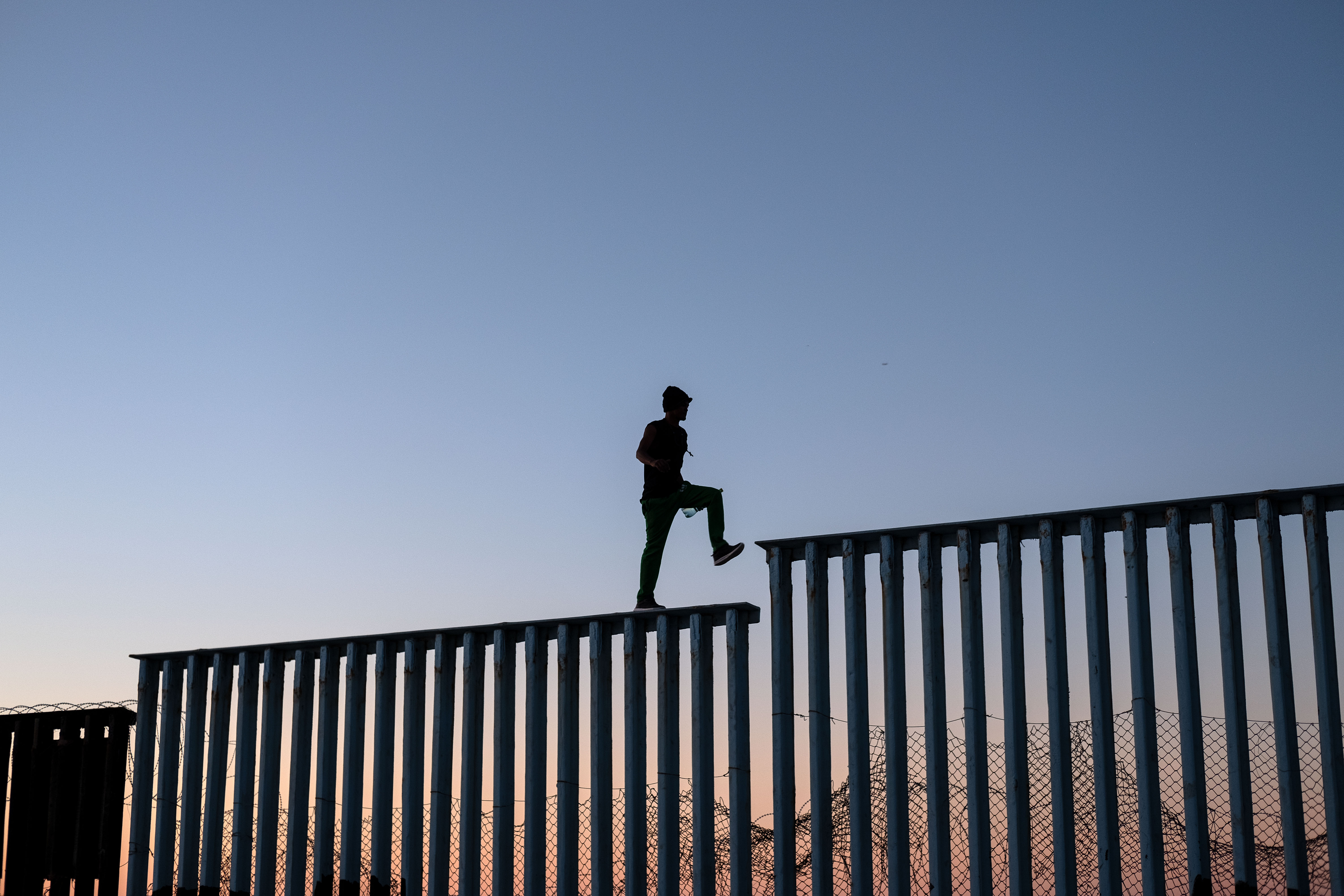 TOPSHOT - A migrant, who claimed not to be part of the Central American migrants moving towards the United States in hopes of a better life, walks on the U.S.-Mexico border fence in Playas de Tijuana, Mexico, on November 14, 2018. - US Defence Secretary Jim Mattis said Tuesday he will visit the US-Mexico border, where thousands of active-duty soldiers have been deployed to help border police prepare for the arrival of a "caravan" of migrants. (Photo by Guillermo Arias / AFP)