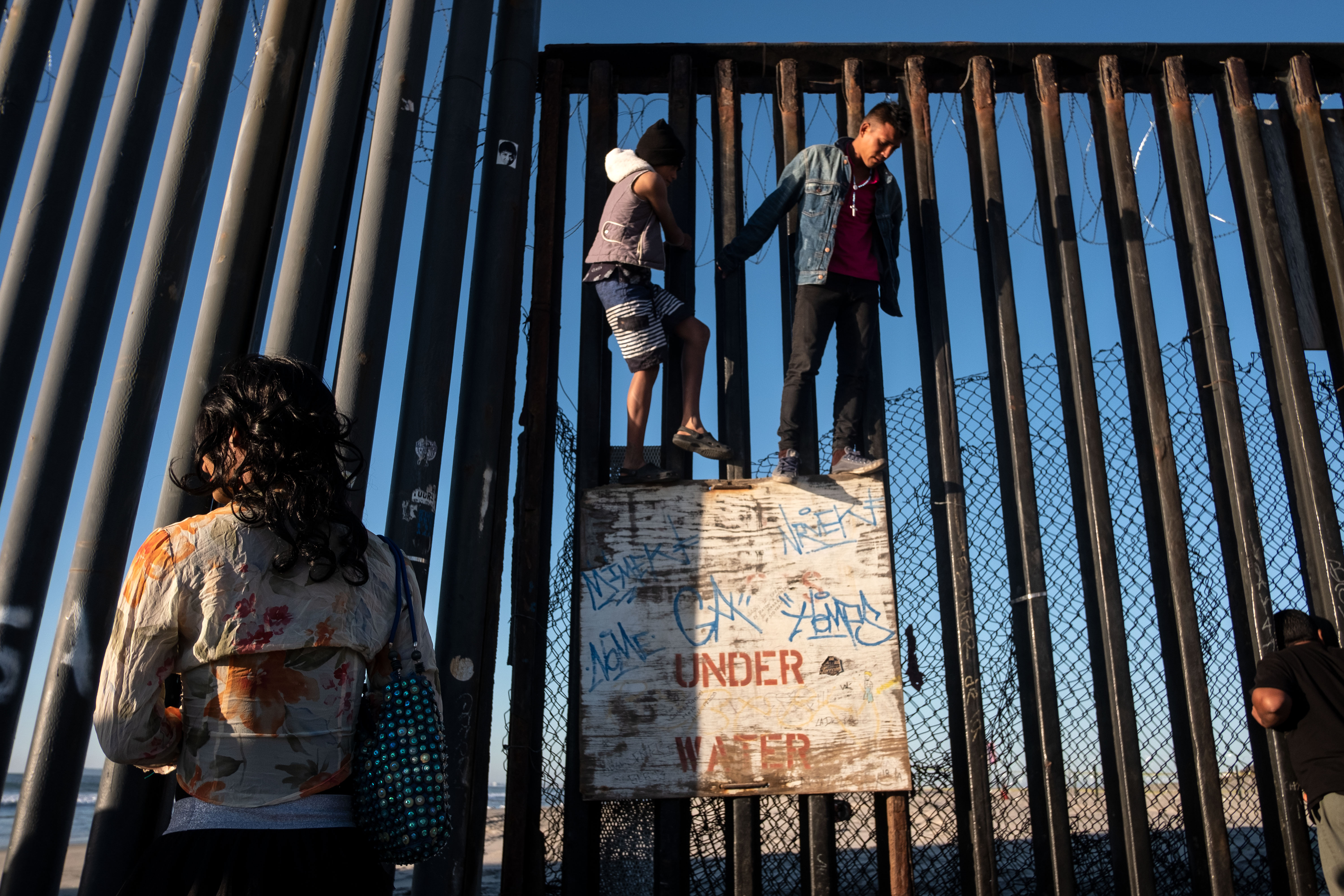Central American migrants moving towards the United States in hopes of a better life, are seen at the US-Mexico border fence in Playas de Tijuana, Mexico, on November 14, 2018. - US Defence Secretary Jim Mattis said Tuesday he will visit the US-Mexico border, where thousands of active-duty soldiers have been deployed to help border police prepare for the arrival of a "caravan" of migrants. (Photo by Guillermo Arias / AFP) 