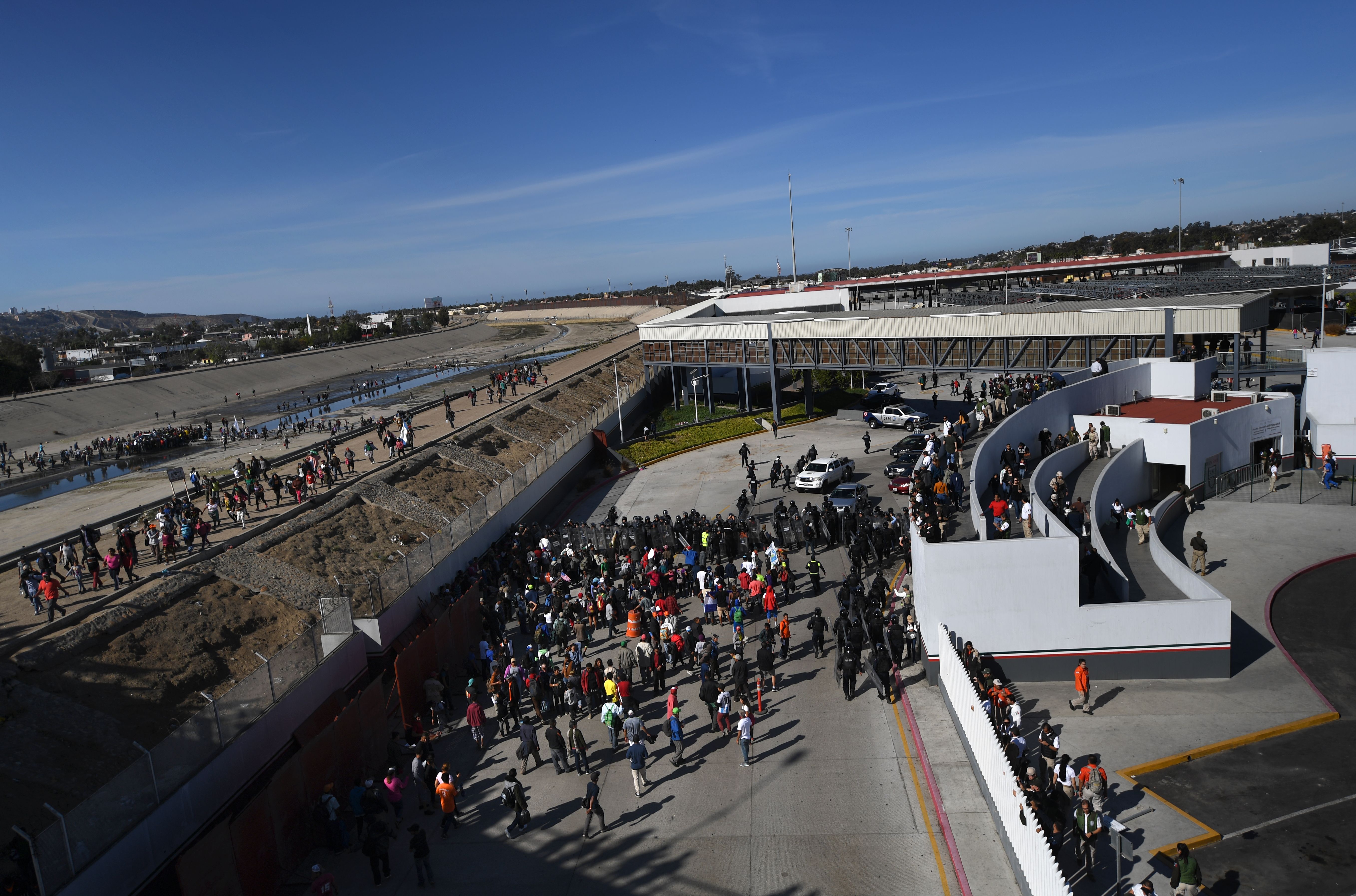 A group of Central American migrants -mostly from Honduras- get to El Chaparral port of entry after crossing the almost dry riverbed of the Tijuana River, in Tijuana, Baja California State, Mexico, on November 25, 2018. - Hundreds of migrants attempted to storm a border fence separating Mexico from the US on Sunday amid mounting fears they will be kept in Mexico while their applications for a asylum are processed. An AFP photographer said the migrants broke away from a peaceful march at a border bridge and tried to climb over a metal border barrier in the attempt to enter the United States. (Photo by Pedro PARDO / AFP) (Photo credit should read PEDRO PARDO/AFP/Getty Images)