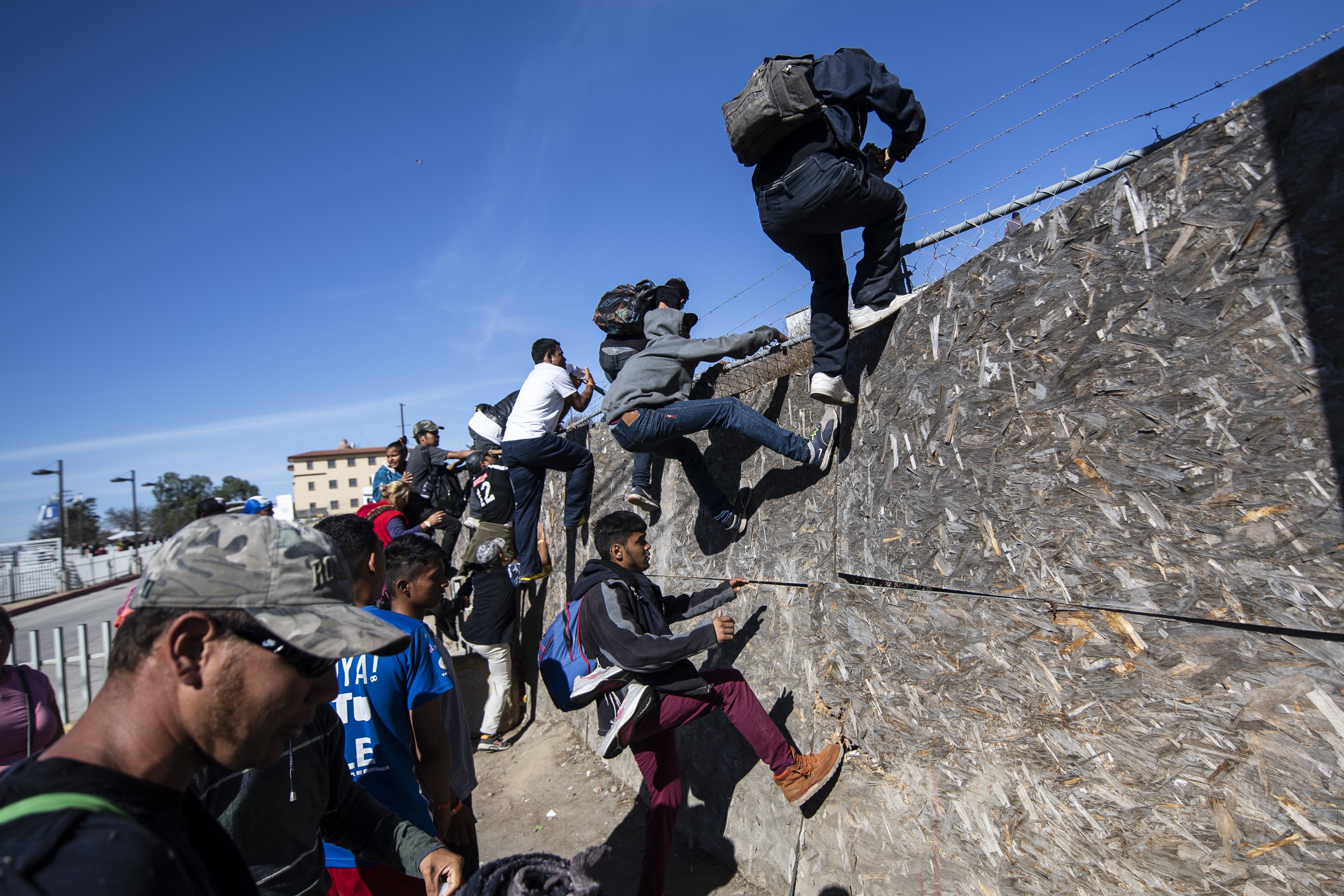 A group of Central American migrants -mostly from Honduras- get over a fence as they try to reach the US-Mexico border near the El Chaparral border crossing in Tijuana, Baja California State, Mexico, on November 25, 2018. - US officials closed the San Ysidro crossing point in southern California on Sunday after hundreds of migrants, part of the "caravan" condemned by President Donald Trump, tried to breach a fence from Tijuana, authorities announced. (Photo by Pedro PARDO / AFP) (Photo credit should read PEDRO PARDO/AFP/Getty Images)
