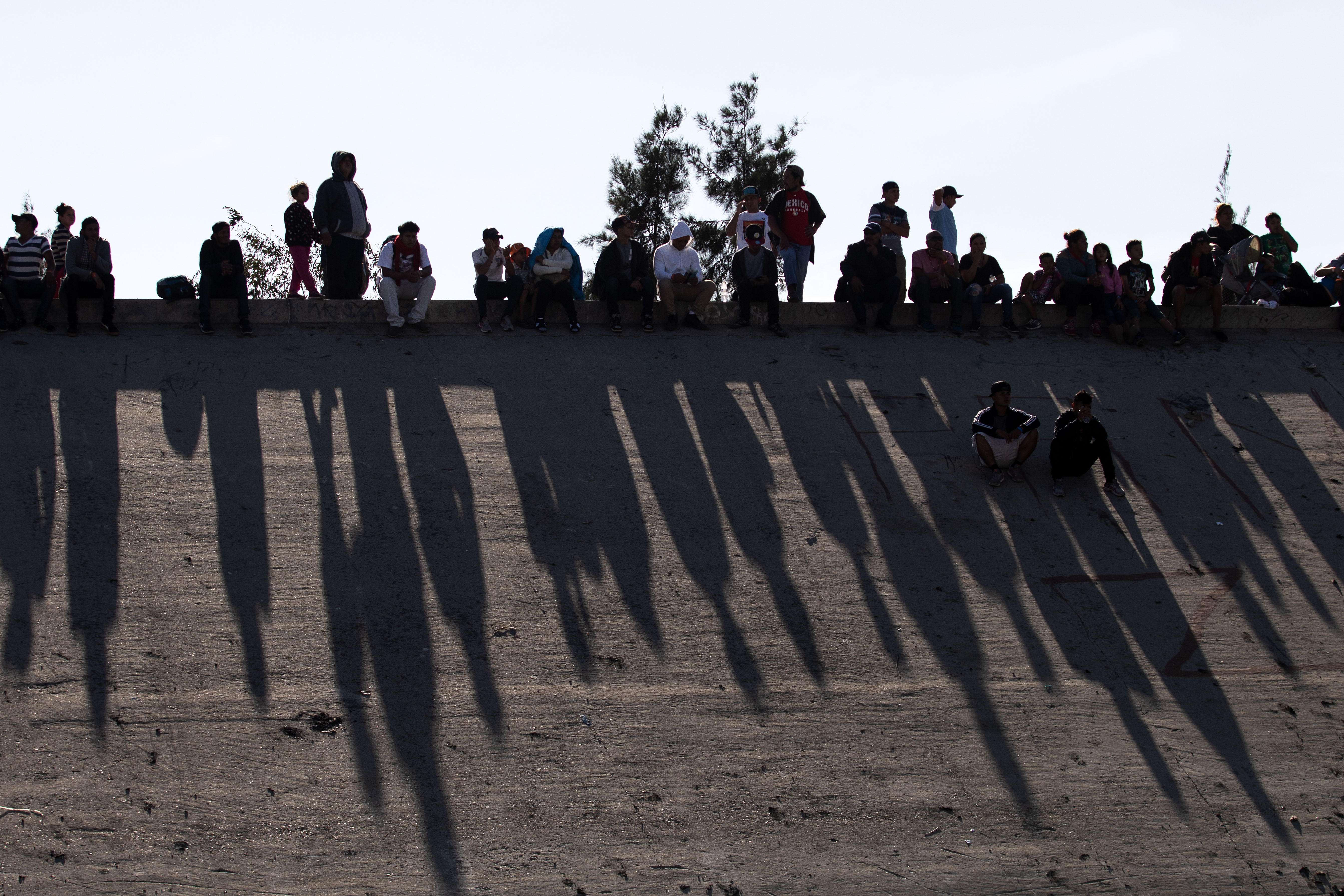  Central American migrants -mostly from Honduras- sit alonh the concrete waterway of the bordering Tijuana River right across the El Chaparral border crossing point in Tijuana, Baja California State, Mexico, on November 25, 2018. - US officials closed the San Ysidro crossing point in southern California on Sunday after hundreds of migrants, part of the 'caravan' condemned by President Donald Trump, tried to breach a fence from Tijuana, authorities announced. (Photo by GUILLERMO ARIAS / AFP)