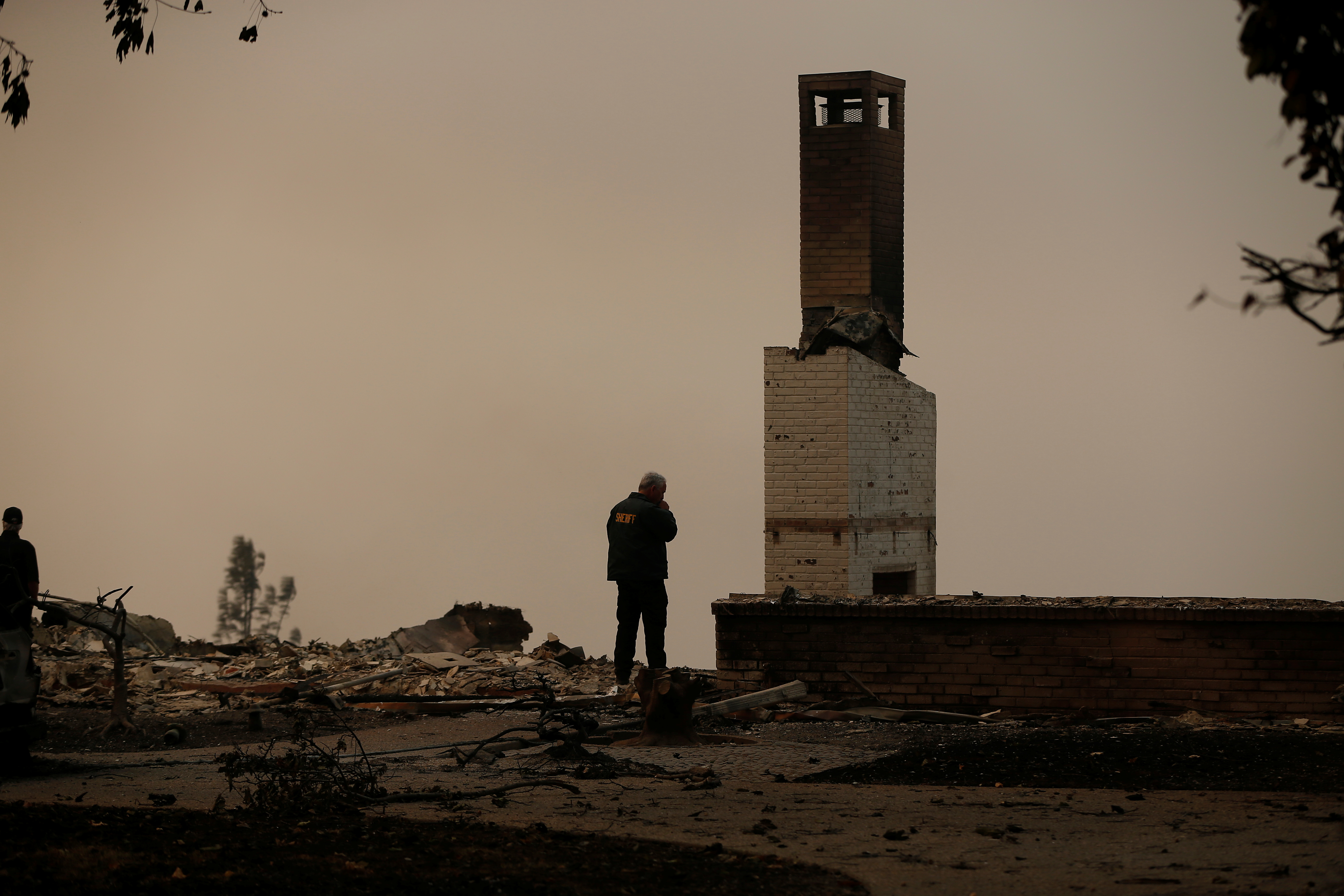 A Butte County Sheriff deputy surveys a burned out home destroyed by the Camp fire in Paradise