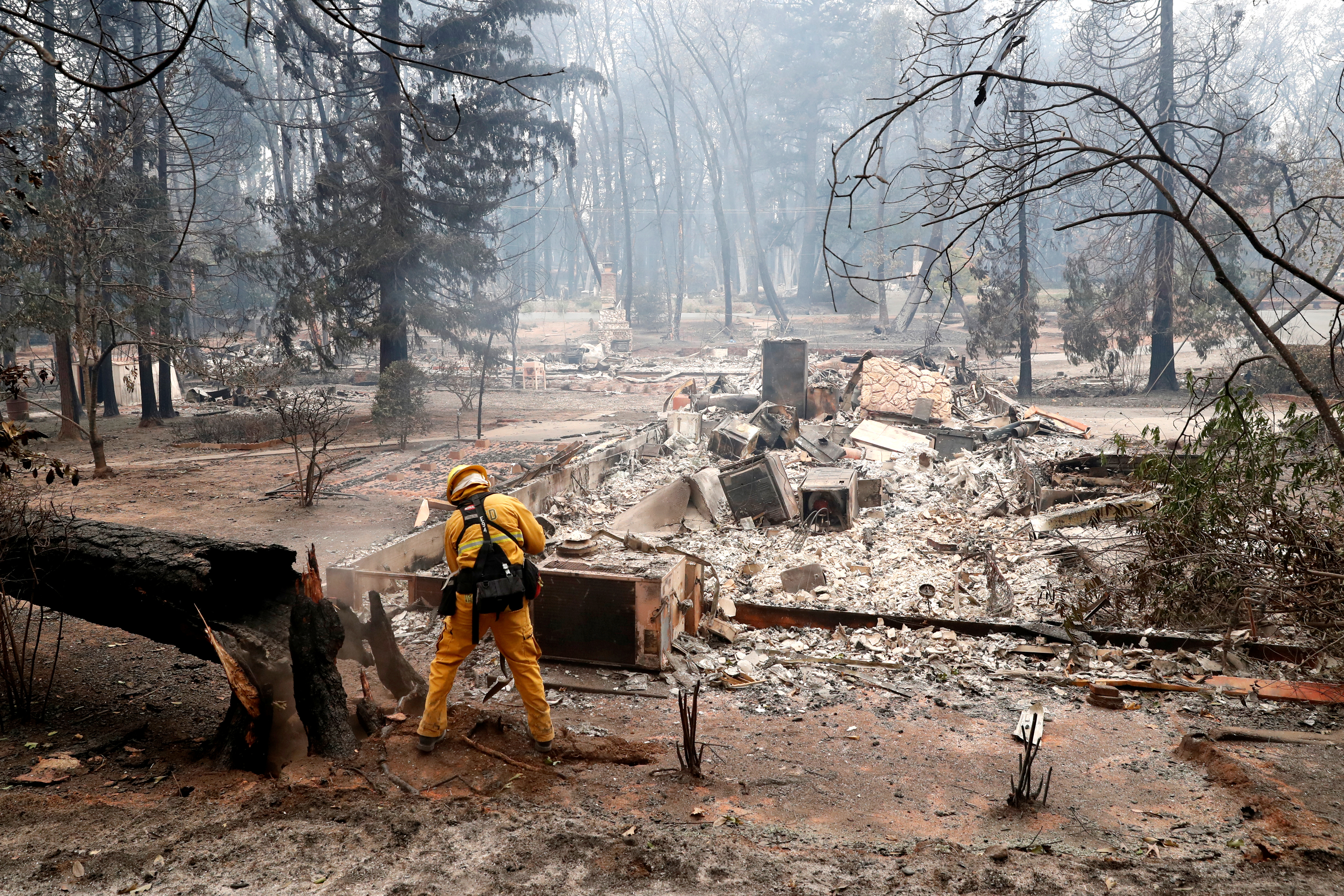 A firefighter extinguishes a hot spot in a neighbourhood destroyed by the Camp Fire in Paradise