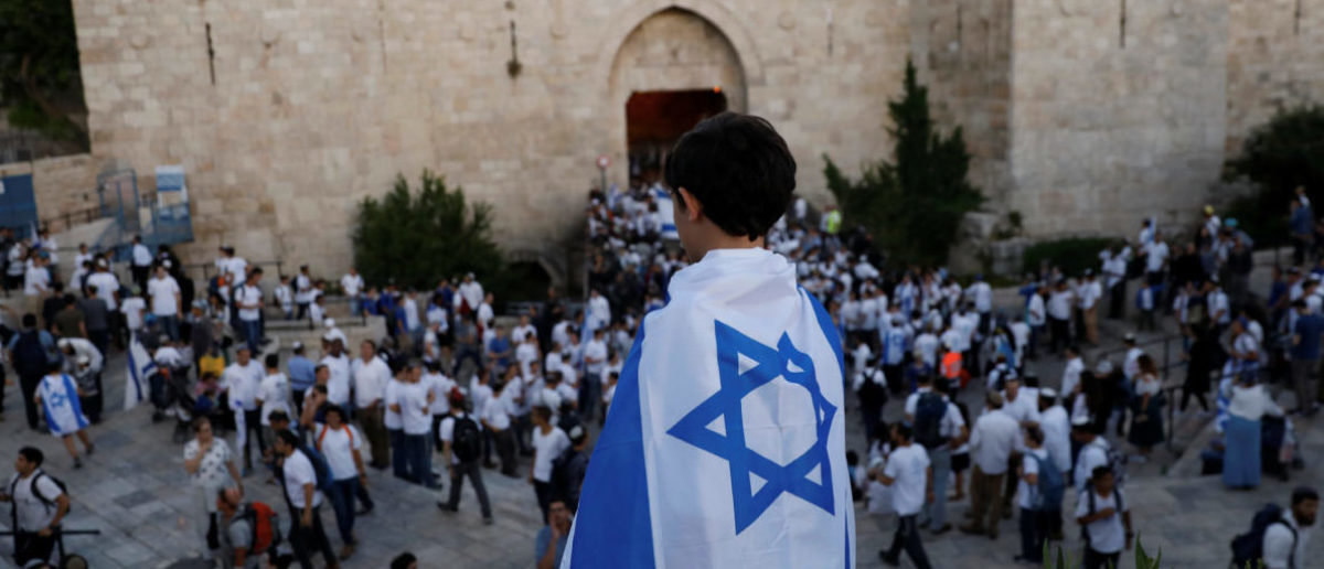 A boy wrapped with Israel's national flag is seen during a parade marking Jerusalem Day, the day in the Jewish calendar when Israel captured East Jerusalem and the Old City from Jordan during the 1967 Middle East War, just outside Damascus Gate outside Jerusalem's Old City May 24, 2017. REUTERS/Ronen Zvulun