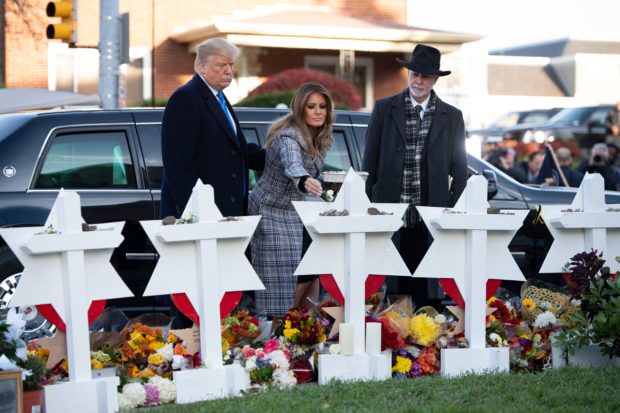 US President Donald Trump and First Lady Melania Trump, alongside Rabbi Jeffrey Myers, place stones and flowers on a memorial as they pay their respects at the Tree of Life Synagogue in Pittsburgh, Pennsylvania, October 30, 2018. - Scores of protesters took to the streets of Pittsburgh to denounce a visit by US President Donald Trump in the wake of a mass shooting at a synagogue that left 11 people dead. Demonstrators gathered near the Tree of Life synagogue, where the shooting took place, holding signs that read "President Hate, Leave Our State!" and "Trump, Renounce White Nationalism Now." (SAUL LOEB/AFP/Getty Images)
