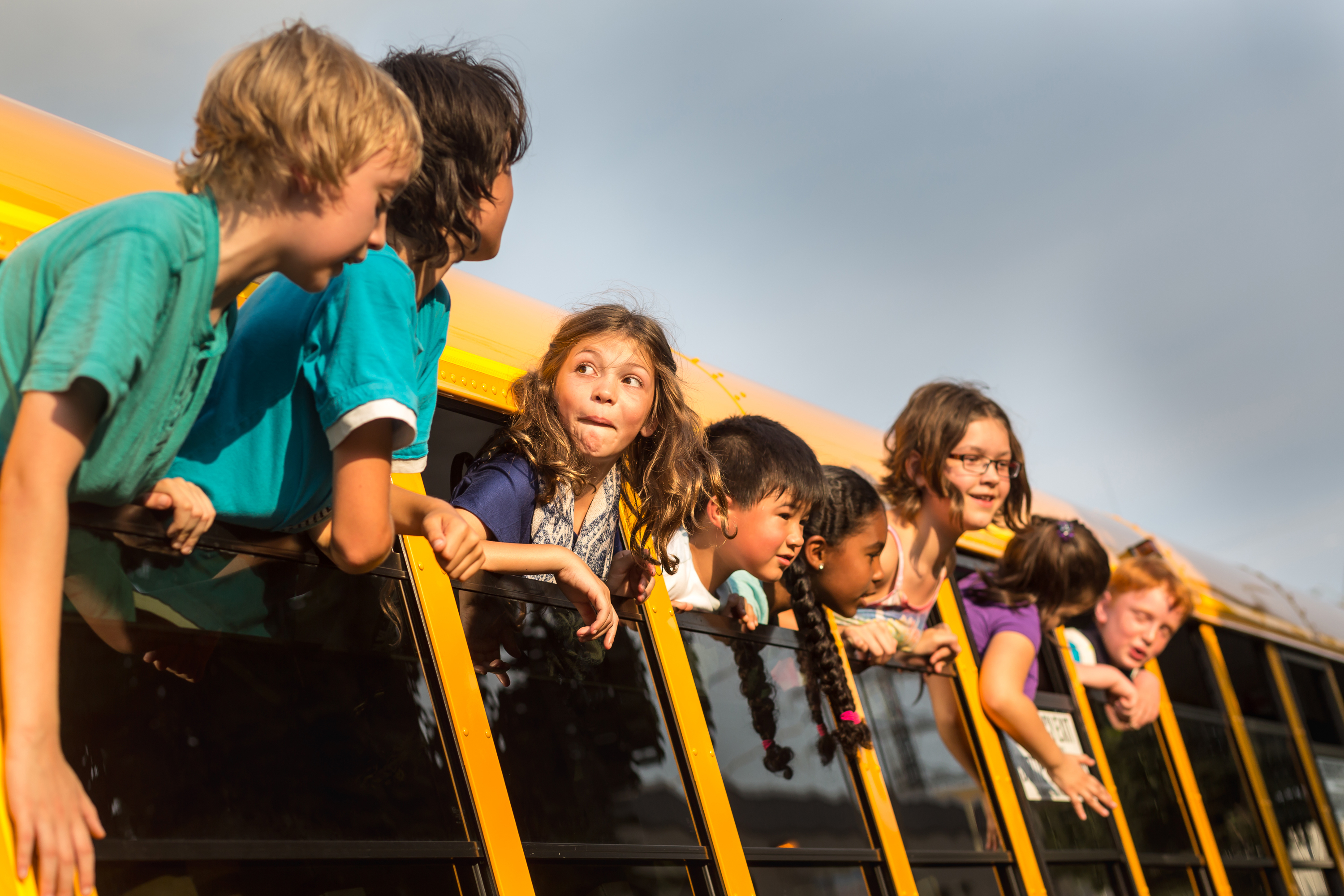 Children on a school bus hanging their heads out the window. SHUTTERSTOCK/ Skyward Kick Productions
