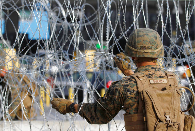 A U.S. Marine sets up a barricade with concertina wire, at the border between Mexico and the U.S., in preparation for the arrival of migrants, in Tijuana, Mexico November 13, 2018. REUTERS/Jorge Duenes