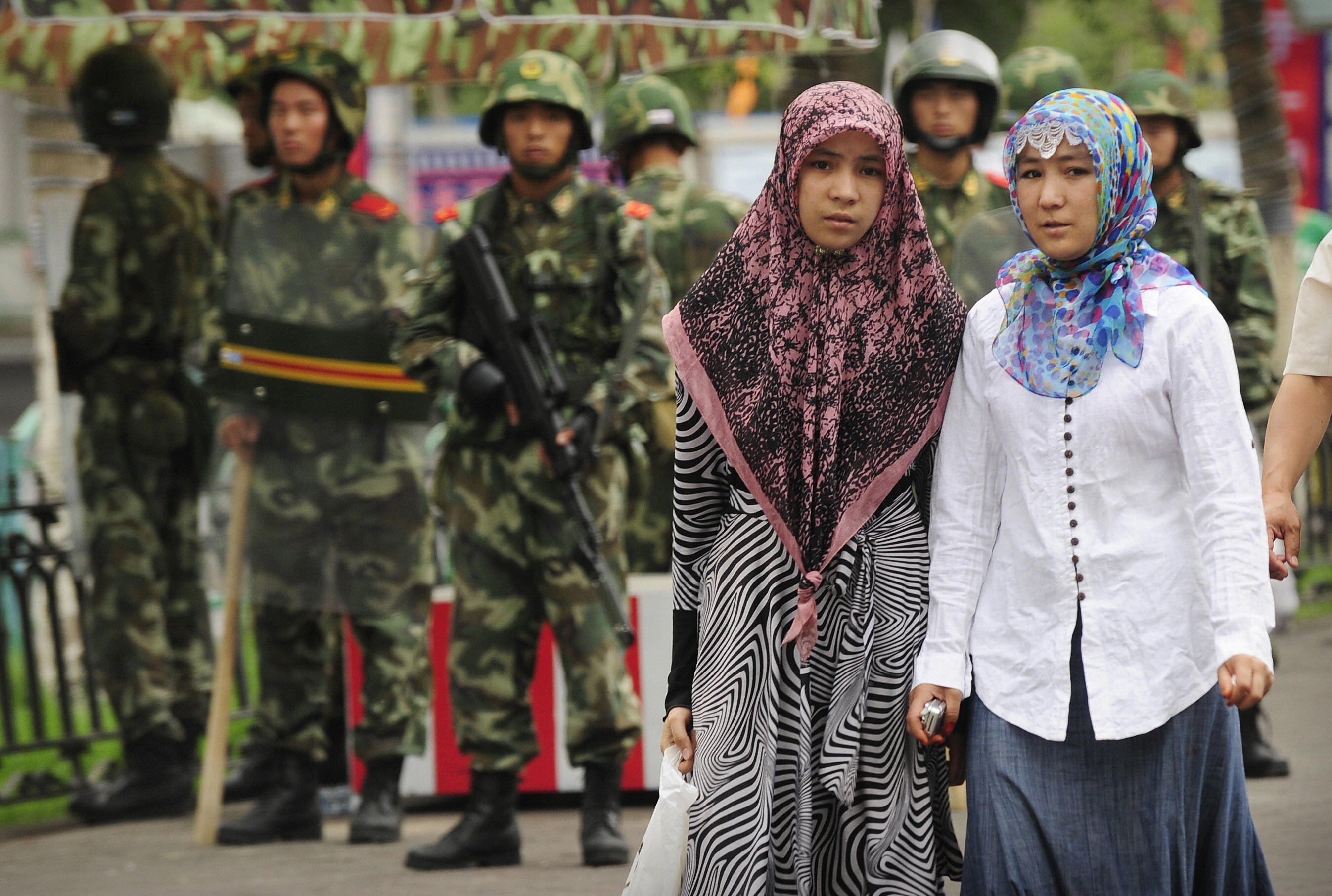 Two ethnic Uighur women pass Chinese paramilitary policemen standing guard outside the Grand Bazaar in the Uighur district of the city of Urumqi in China's Xinjiang region on July 14, 2009. A mosque was closed and many businesses were shuttered a day after police shot dead two Muslim Uighurs, as ethnic tensions simmered in restive Urumqi. (PETER PARKS/AFP/Getty Images)