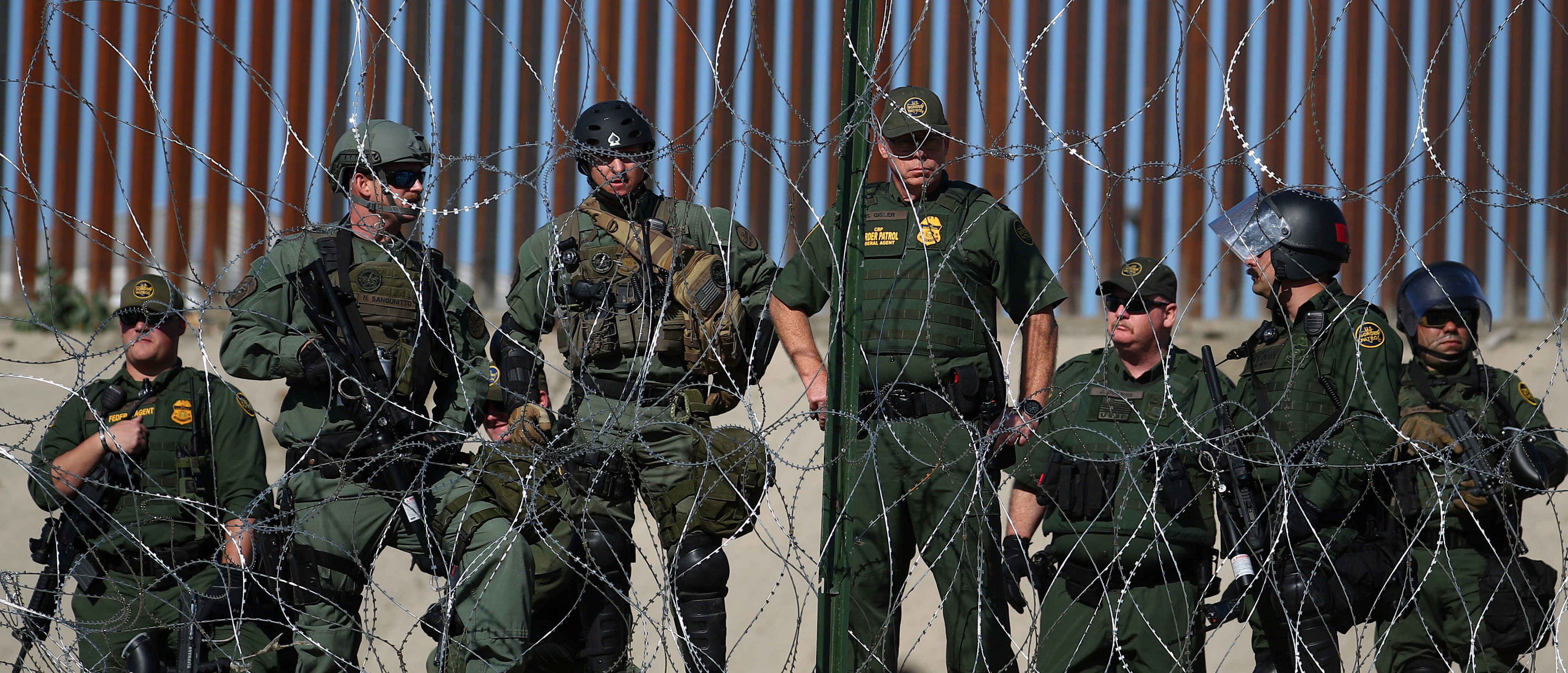 U.S border patrol stand near the border fence between Mexico and the United States as migrants stand near by in Tijuana, Mexico, November 25, 2018. REUTERS/Hannah McKay