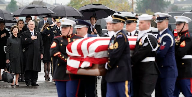 Former President George W. Bush and Laura Bush watch as the flag-draped casket of former President George H.W. Bush is carried by a joint services military honor guard to a Union Pacific train on December 6, 2018 in Houston, Texas. President Bush will be buried at his final resting place at the George H.W. Bush Presidential Library at Texas A&M University in College Station, Texas. A WWII combat veteran, Bush served as a member of Congress from Texas, ambassador to the United Nations, director of the CIA, vice president and 41st president of the United States. (Photo by David J. Phillip-Pool/Getty Images)