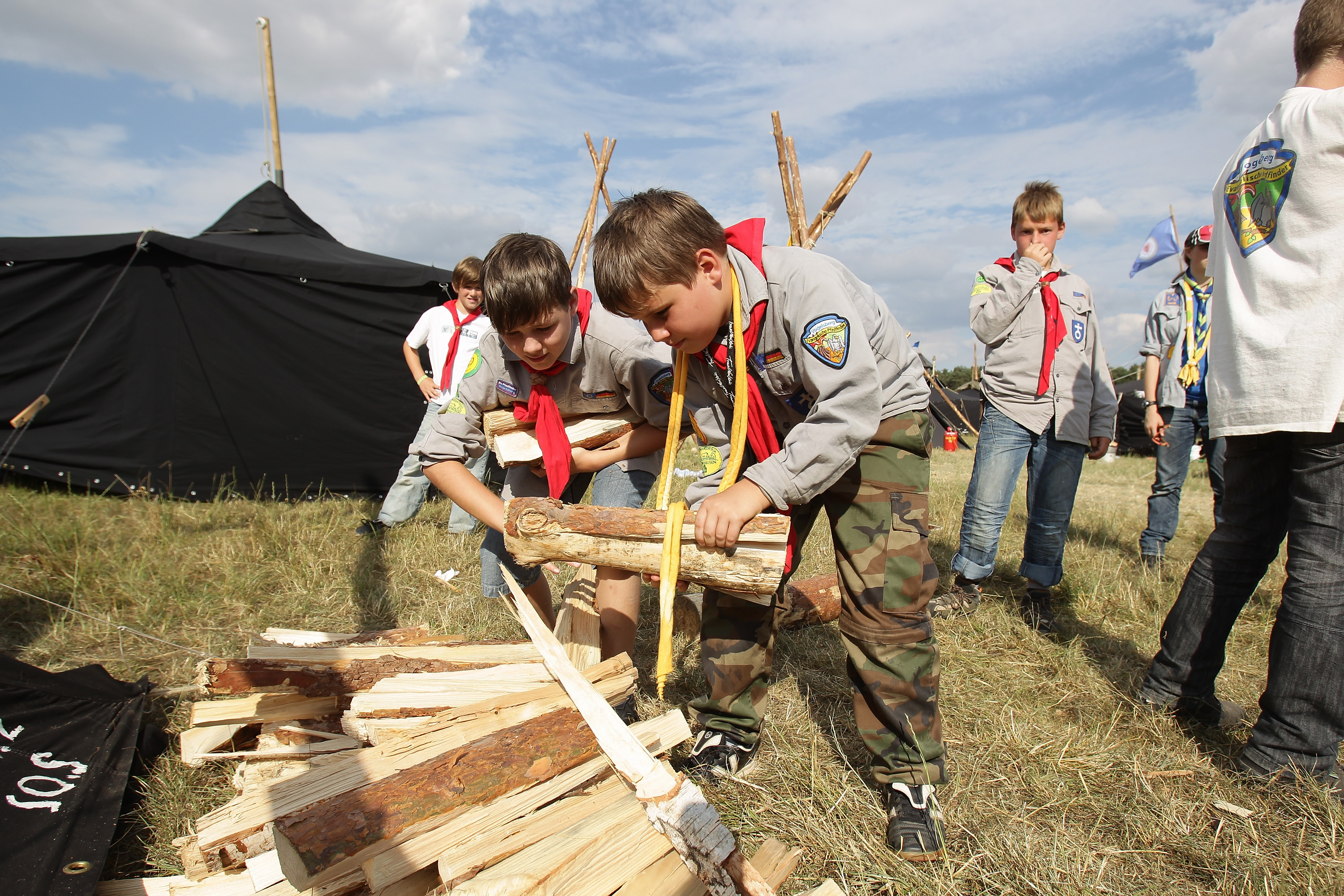 ALMKE, GERMANY - JULY 31: Scoust carry firewood at the camp on July 31, 2010 in Almke near Wolfsburg, Germany. About 5000 young scouts from Germany, Russia, Belgium, Suisse, USA and Italy aged 12 to 20 participate in a camp. Since 1973, the German VCP-Christian Guides and Pathfinders organisation, offers an International historic boys and girls scout meeting during the summer holidays. On a 25 hectare field include 1370 tens, a tent church and a tent theater. The Federal camp is held every four years. (Photo by Andreas Rentz/Getty Images)