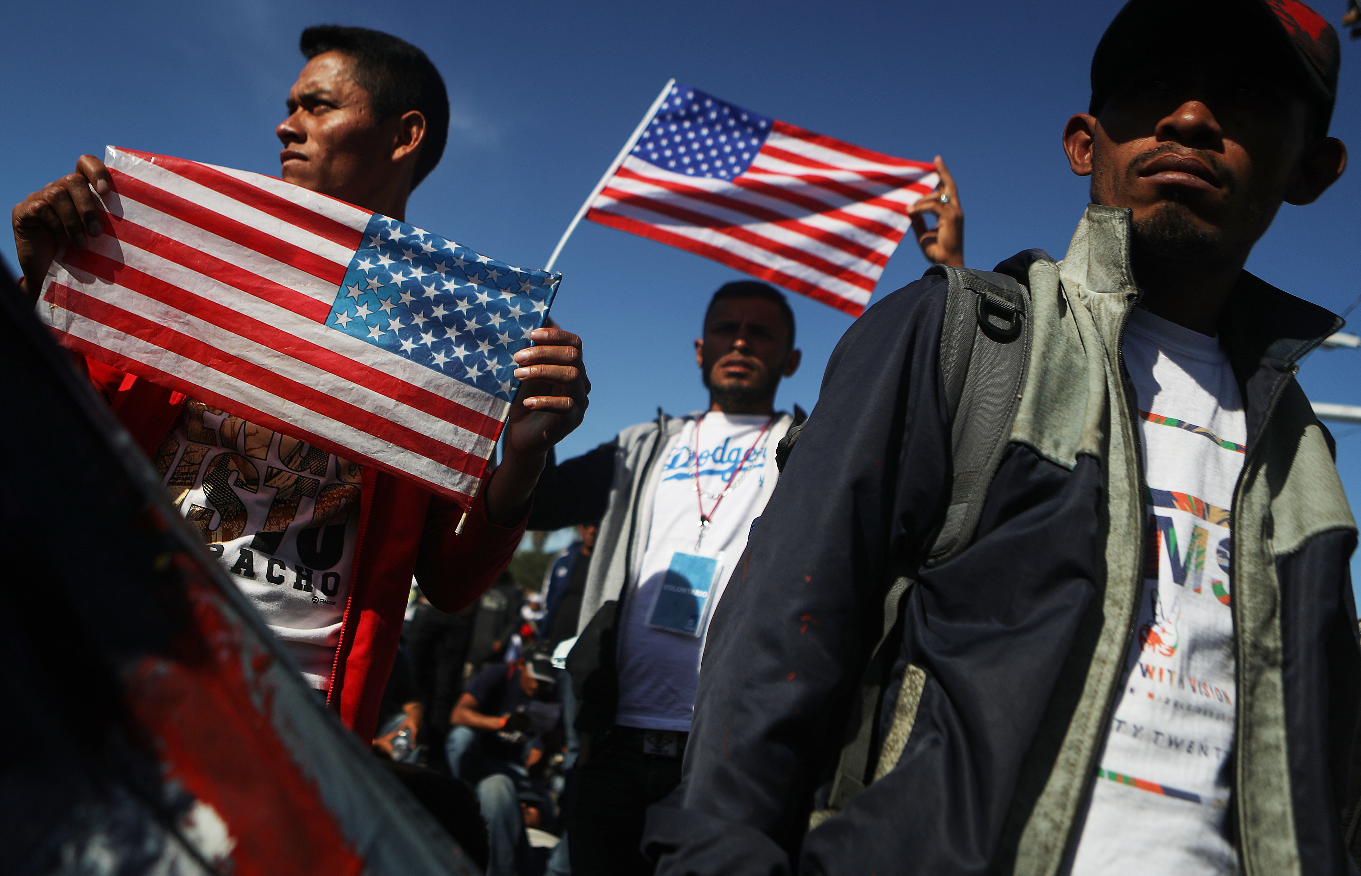 TIJUANA, MEXICO - NOVEMBER 25: Migrants hold American flags during a peaceful march shortly before some evaded a police blockade and rushed toward the El Chaparral port of entry on November 25, 2018 in Tijuana, Mexico. U.S. Customs and Border Protection temporarily closed the two ports of entry on the border with Tijuana in response. Around 6,000 migrants from Central America have arrived in the city with the mayor of Tijuana declaring the situation a 'humanitarian crisis'. (Photo by Mario Tama/Getty Images)