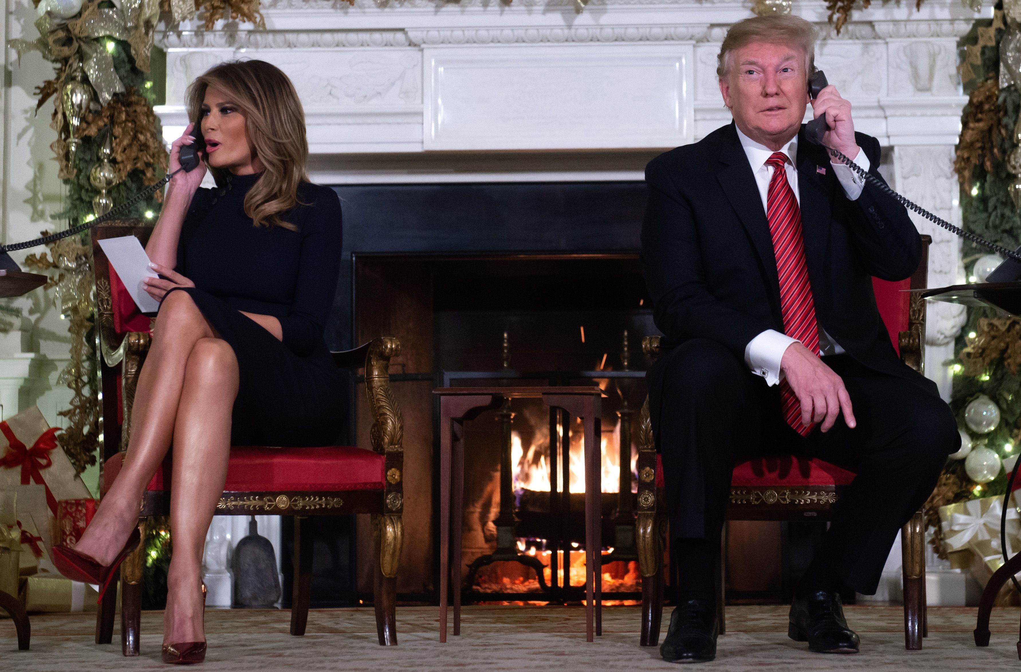TOPSHOT - US President Donald Trump and First Lady Melania Trump speak on the telephone as they answers calls from people calling into the NORAD Santa tracker phone line in the State Dining Room of the White House in Washington, DC, on December 24, 2018. (Photo by SAUL LOEB/AFP/Getty Images)