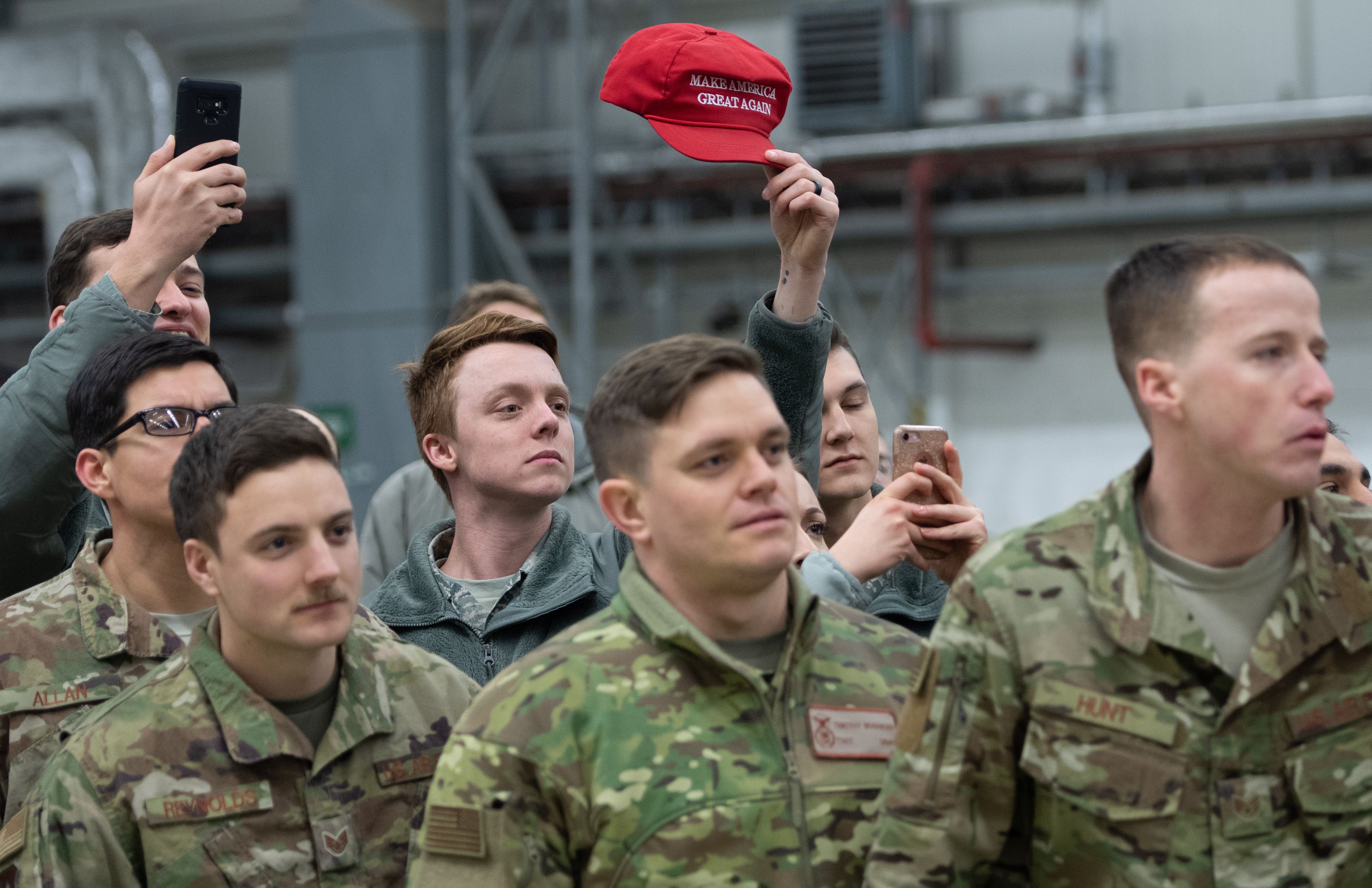 A member of the US military holds up a "Make America Great Again" hat as US President Donald Trump and First Lady Melania Trump greet members of the US military during a stop at Ramstein Air Base in Germany, on December 27, 2018. - President Donald Trump used a lightning visit to Iraq -- his first with US troops in a conflict zone since being elected -- to defend the withdrawal from Syria and to declare an end to America's role as the global "policeman." (Photo by SAUL LOEB/AFP/Getty Images)