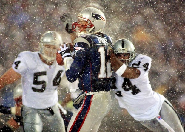 FOXBORO, UNITED STATES: New England Patriots quarterback Tom Brady (C) takes a hit from Charles Woodson (R) of the Oakland Raiders on a pass attempt in the last two minutes of the game in their AFC playoff 19 January 2002 in Foxboro, Massachusetts. The Patriots won 16-13 in overtime. AFP PHOTO/Matt CAMPBELL (Photo credit should read MATT CAMPBELL/AFP/Getty Images)