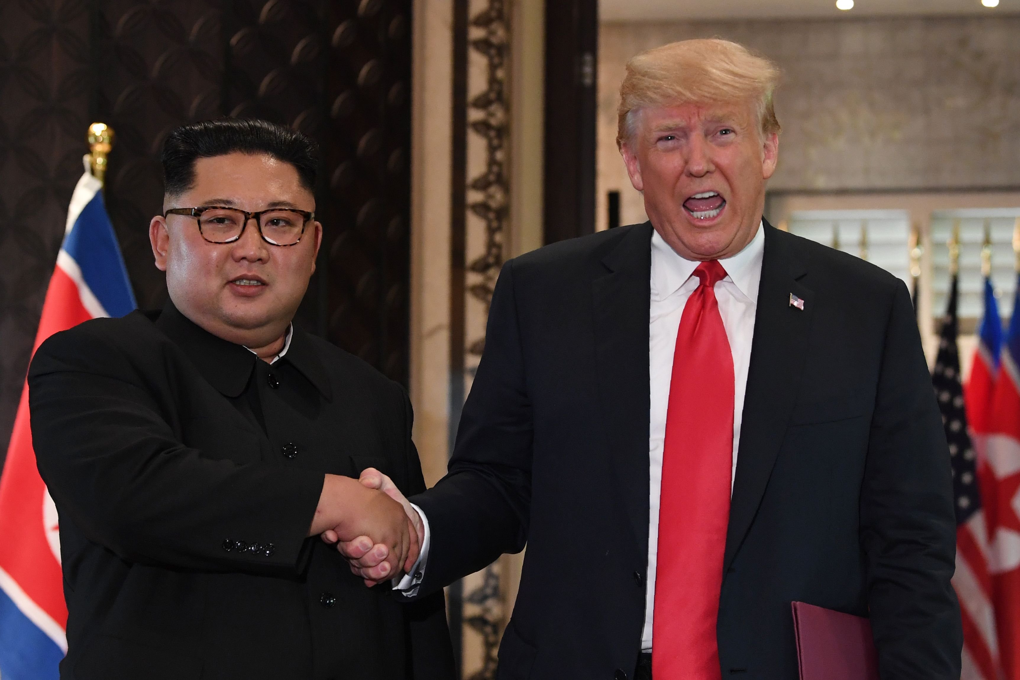 TOPSHOT - US President Donald Trump (R) and North Korea's leader Kim Jong Un shake hands following a signing ceremony during their historic US-North Korea summit, at the Capella Hotel on Sentosa island in Singapore on June 12, 2018. - Donald Trump and Kim Jong Un became on June 12 the first sitting US and North Korean leaders to meet, shake hands and negotiate to end a decades-old nuclear stand-off. (Photo by SAUL LOEB / AFP) 