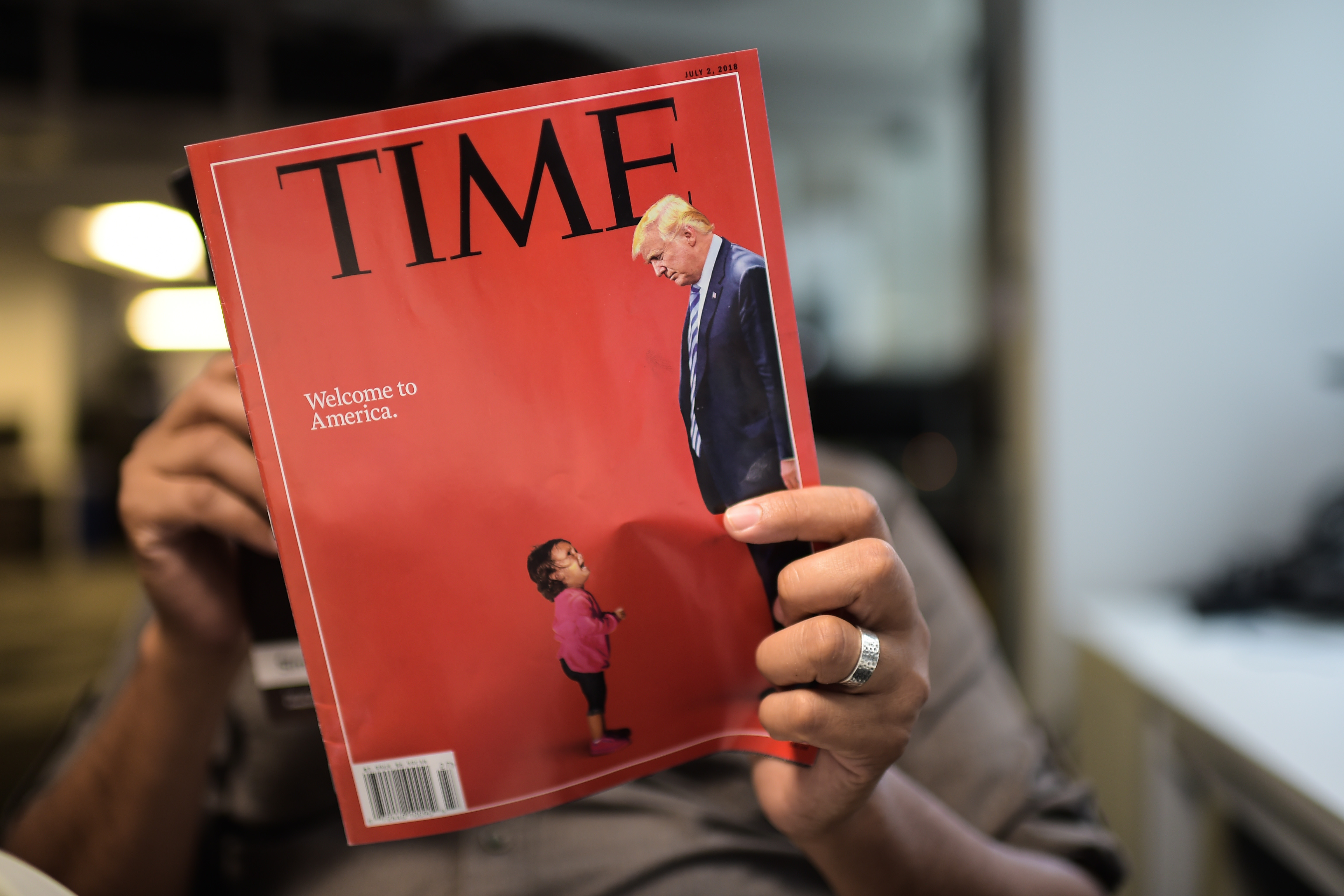 Un journaliste de l'AFP lit un exemplaire de Time Magazine avec une couverture, combinant des images montrant un enfant en pleurs pris à la frontière américaine au Mexique et une image du président américain Donald Trump, le 22 juin 2018, à Washington. (Photo: ERIC BARADAT / AFP / Getty Images)