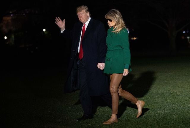 US President Donald Trump waves next to First Lady Melania Trump as they arrive at the White House in Washington, DC, on December 27, 2018, as they return from an unannounced trip to Iraq. - President Donald Trump used a lightning visit to Iraq -- his first with US troops in a conflict zone since being elected -- to defend the withdrawal from Syria and to declare an end to America's role as the global "policeman." (Photo credit: NICHOLAS KAMM/AFP/Getty Images)