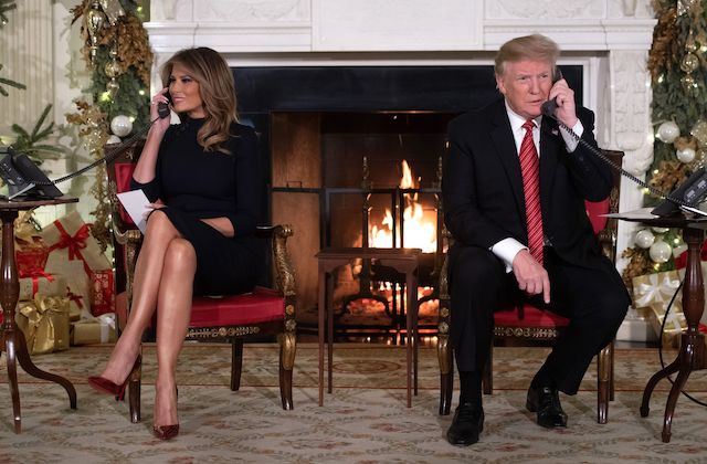 US President Donald Trump and First Lady Melania Trump speak on the telephone as they answers calls from people calling into the NORAD Santa tracker phone line in the State Dining Room of the White House in Washington, DC, on December 24, 2018. (Photo credit: SAUL LOEB/AFP/Getty Images)