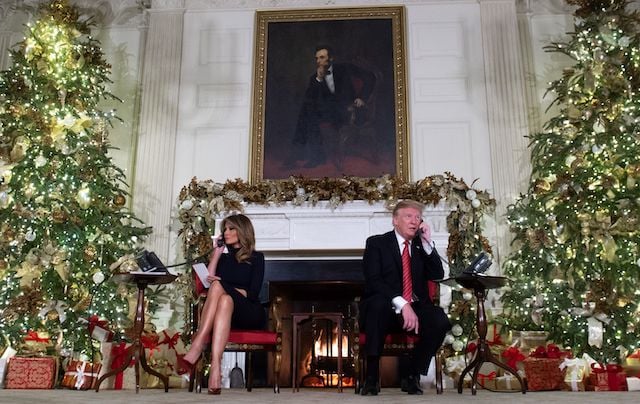 US President Donald Trump and First Lady Melania Trump speak on the telephone as they answers calls from people calling into the NORAD Santa tracker phone line in the State Dining Room of the White House in Washington, DC, on December 24, 2018. (Photo credit: SAUL LOEB/AFP/Getty Images)